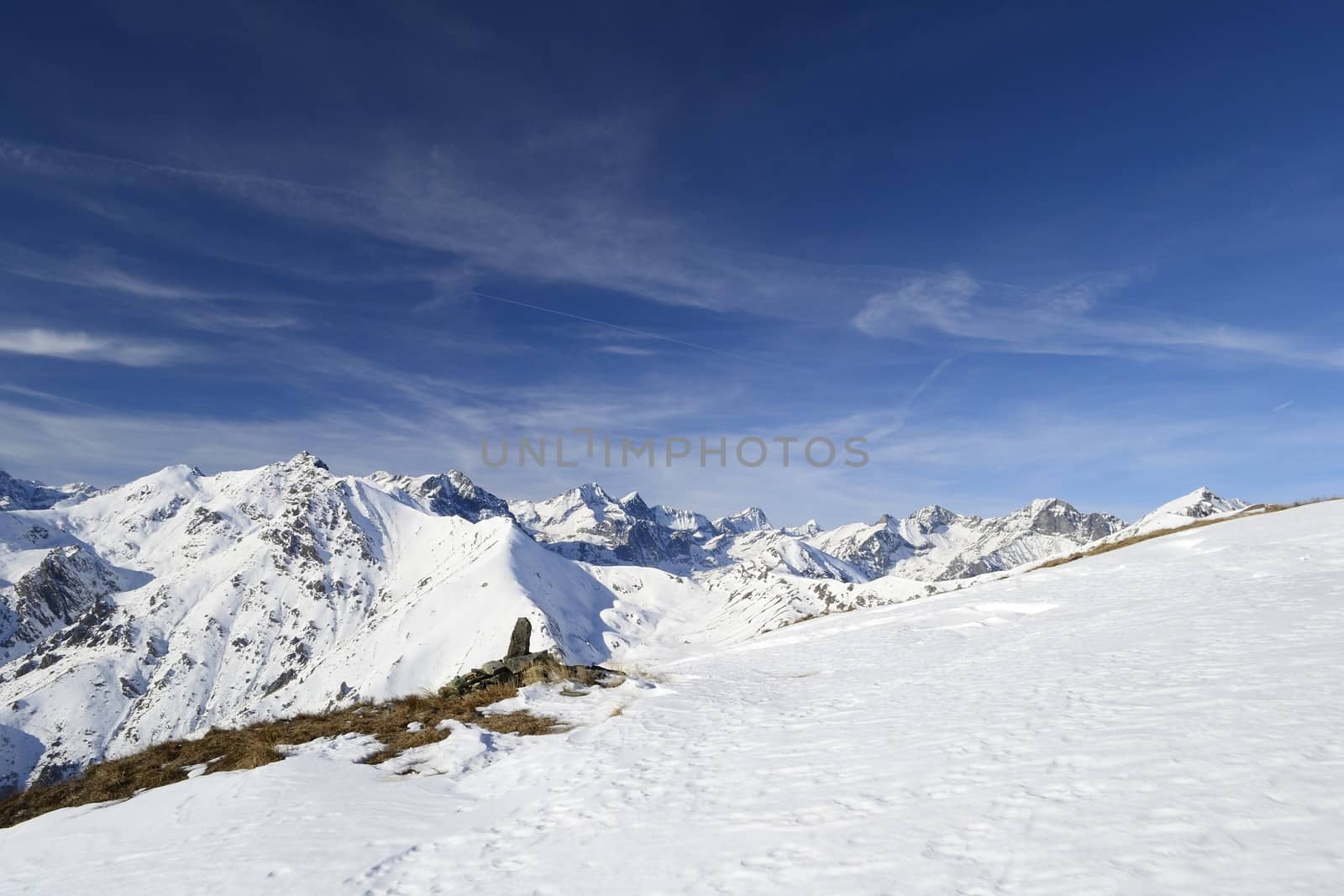 Candid off-piste ski slope in scenic background of mountain peaks, valleys and plain. Piedmont, Italian Alps