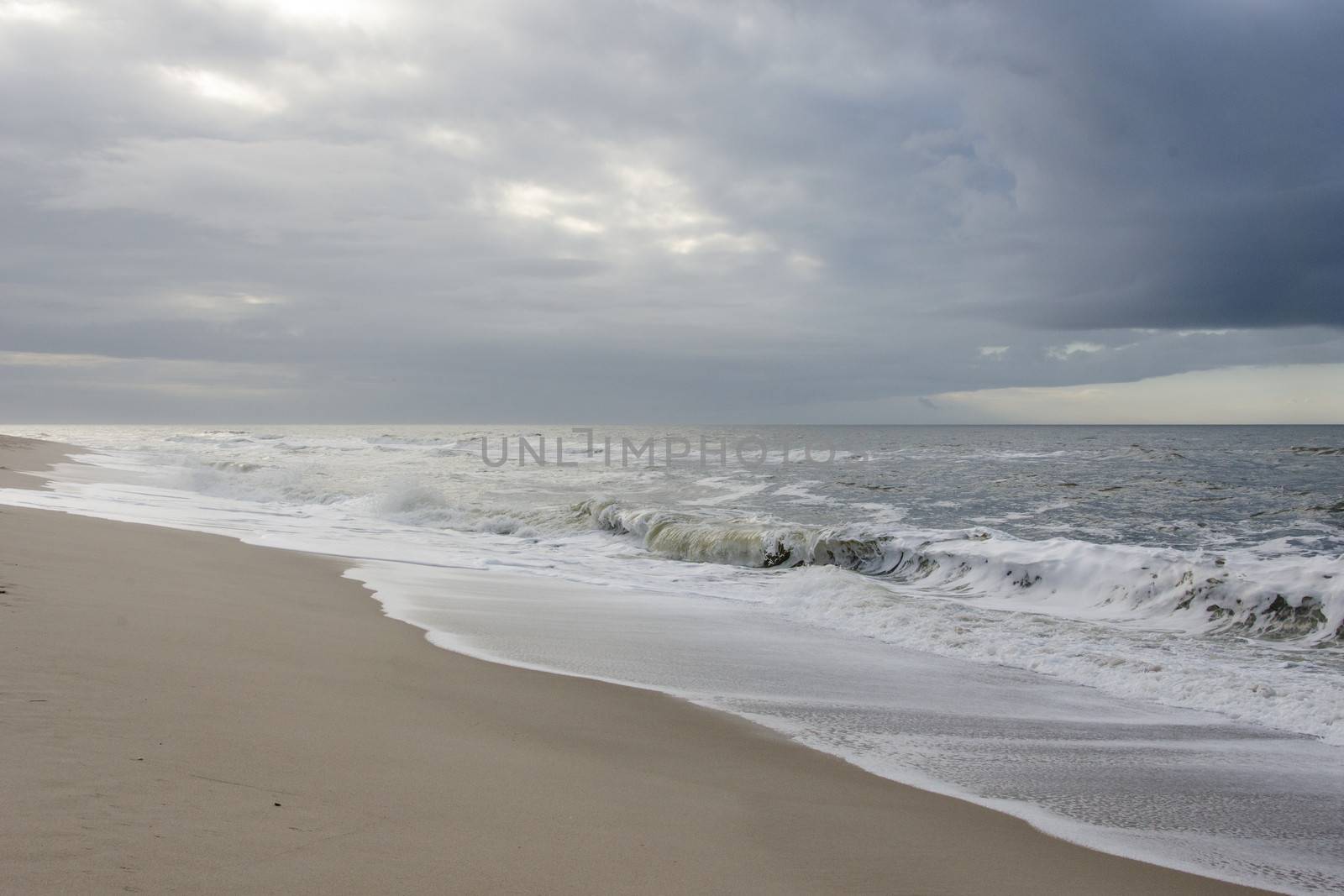 Beach with waves and gray rain clouds on a windy day