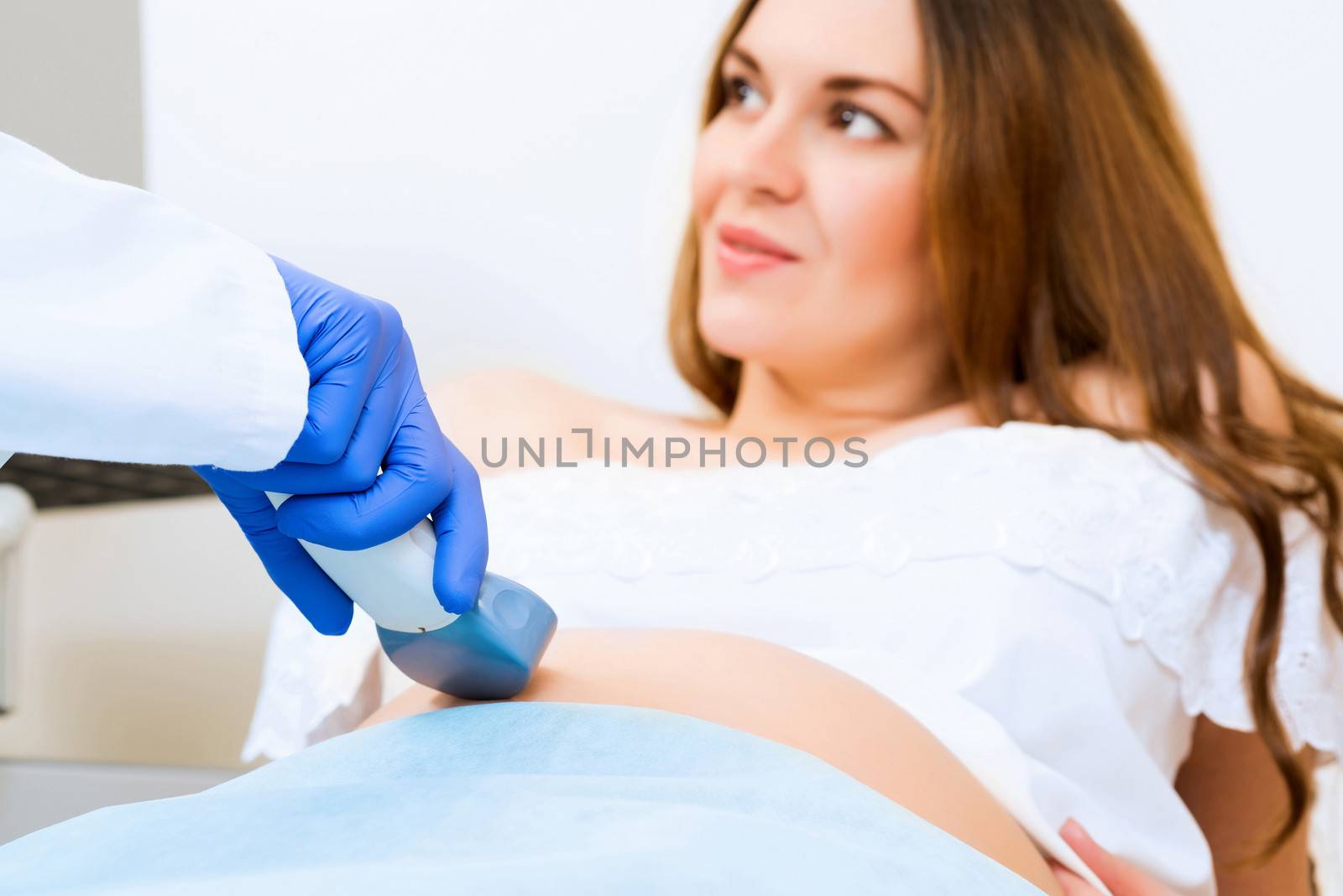 close-up of hands and abdominal ultrasound scanner for pregnant women