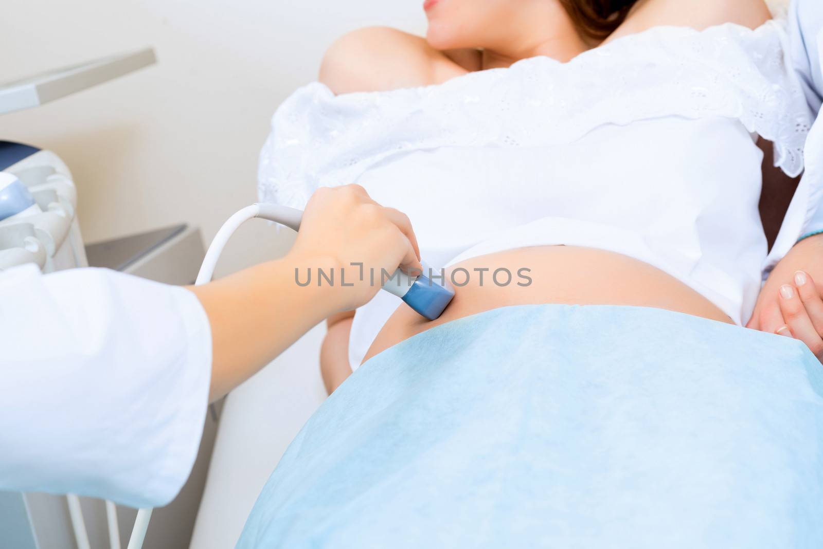 close-up of hands and abdominal ultrasound scanner for pregnant women