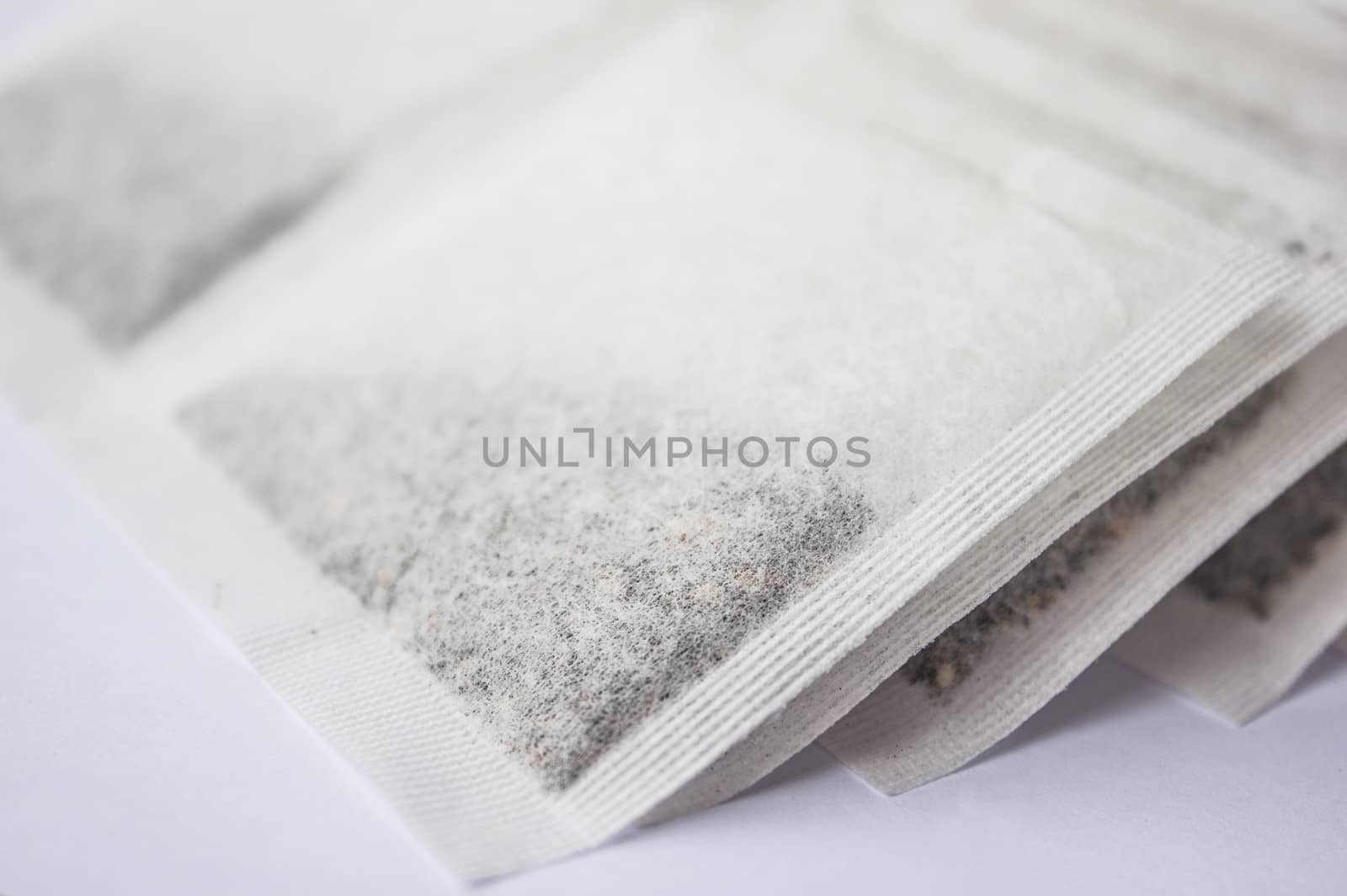 Multiple tea bags lying around on a white background.