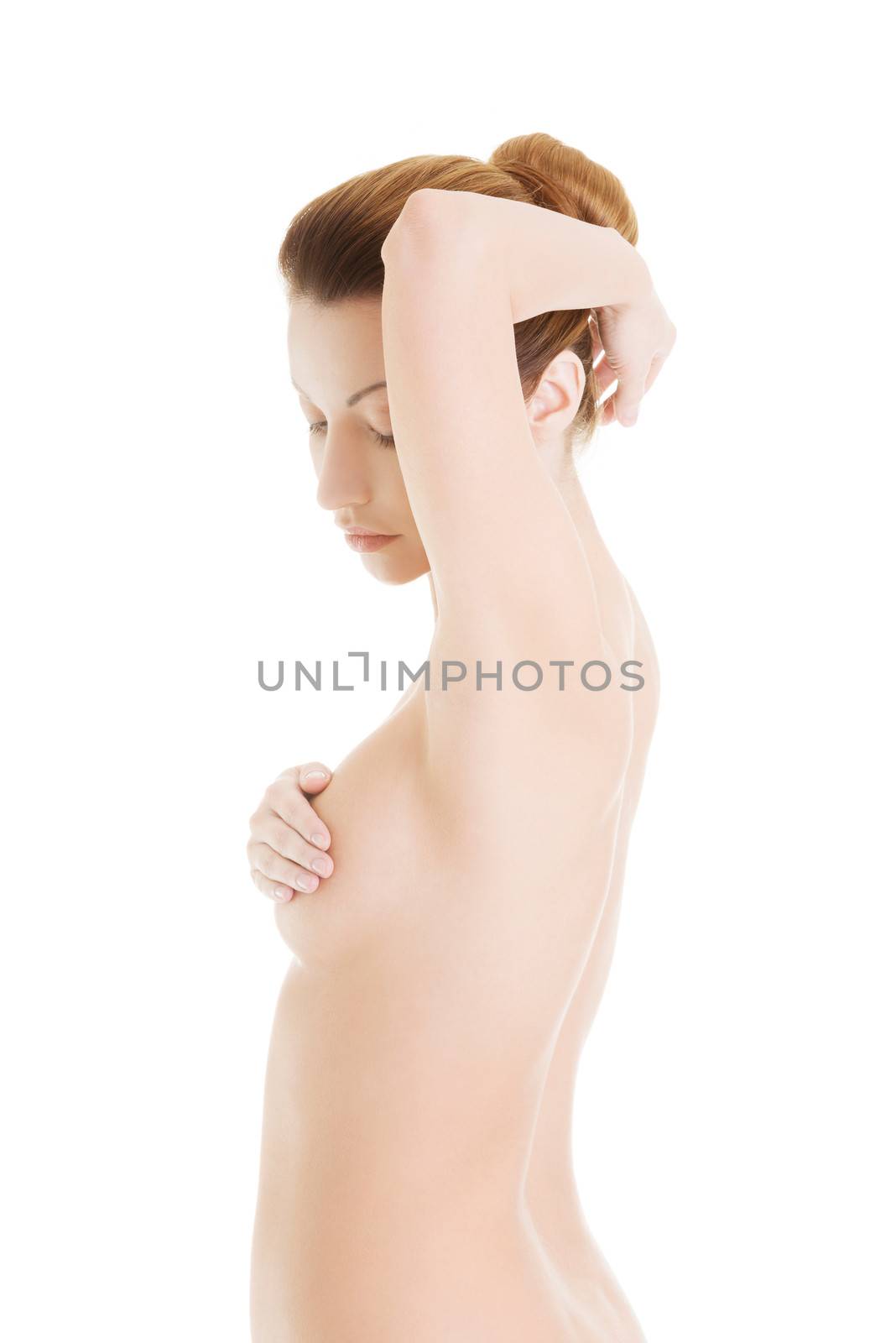 Caucasian adult woman examining her breast for lumps or signs of breast cancer