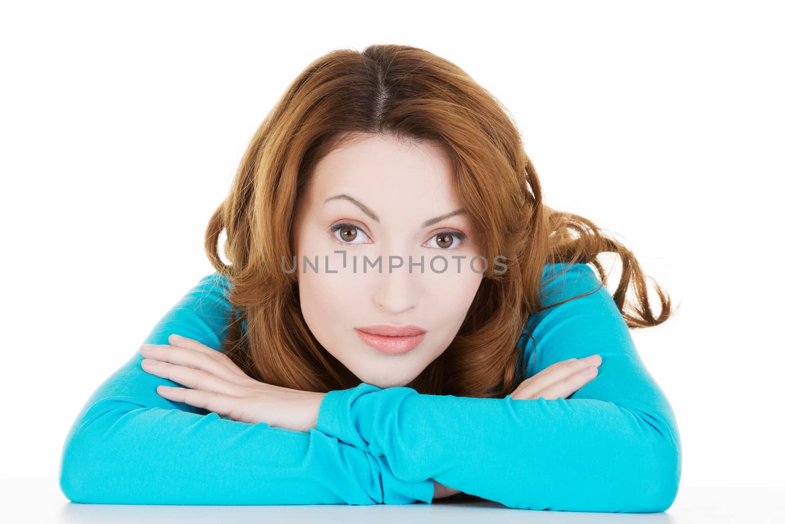 Pretty, happy, young woman in casual clothes sitting at the desk, isolated on white