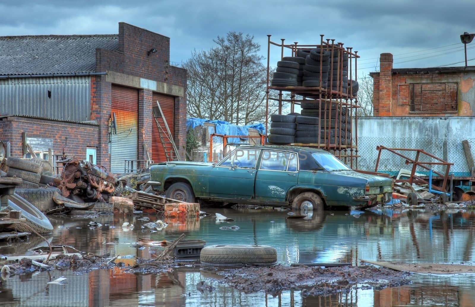 Scrapyard showing flood water and old car, Worcestershire, England.