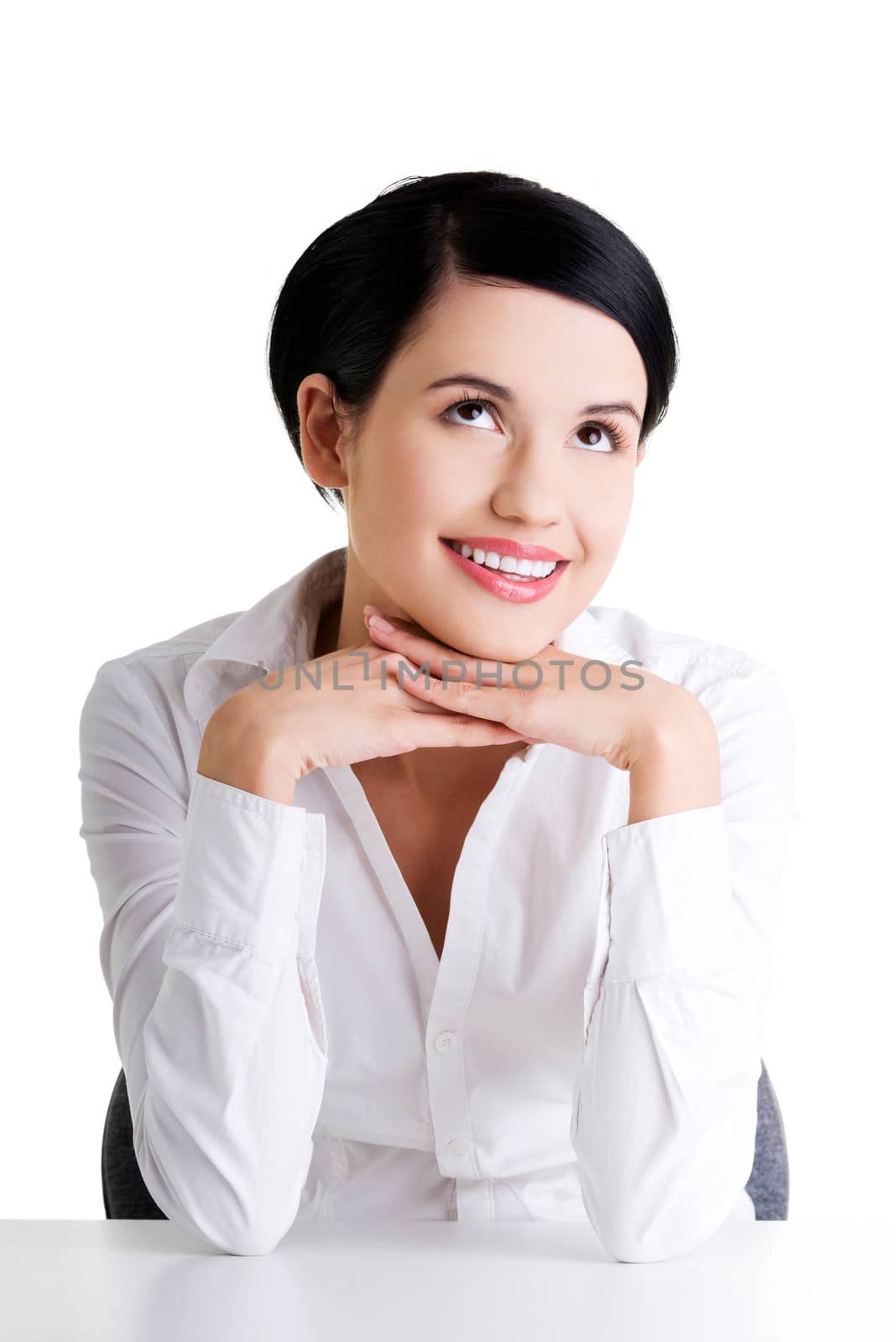 Young beautiful happy businesswoman behind the desk looking up on copy space, isolated