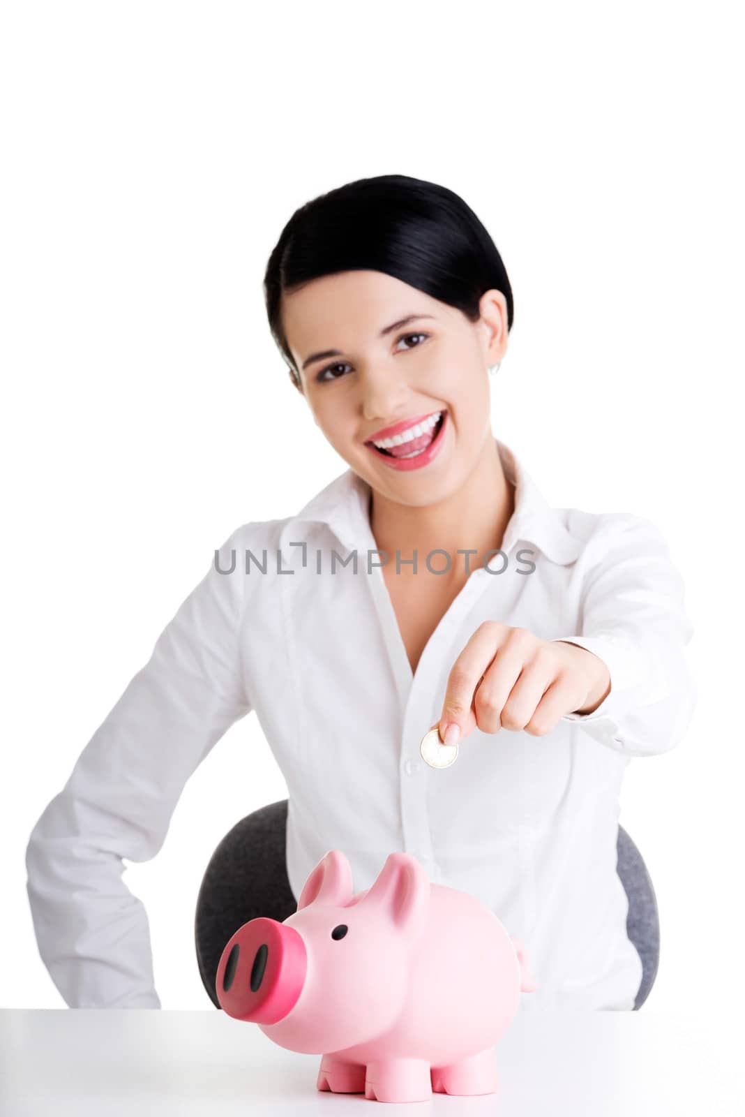 Businesswoman putting a coin into a piggy bank by BDS