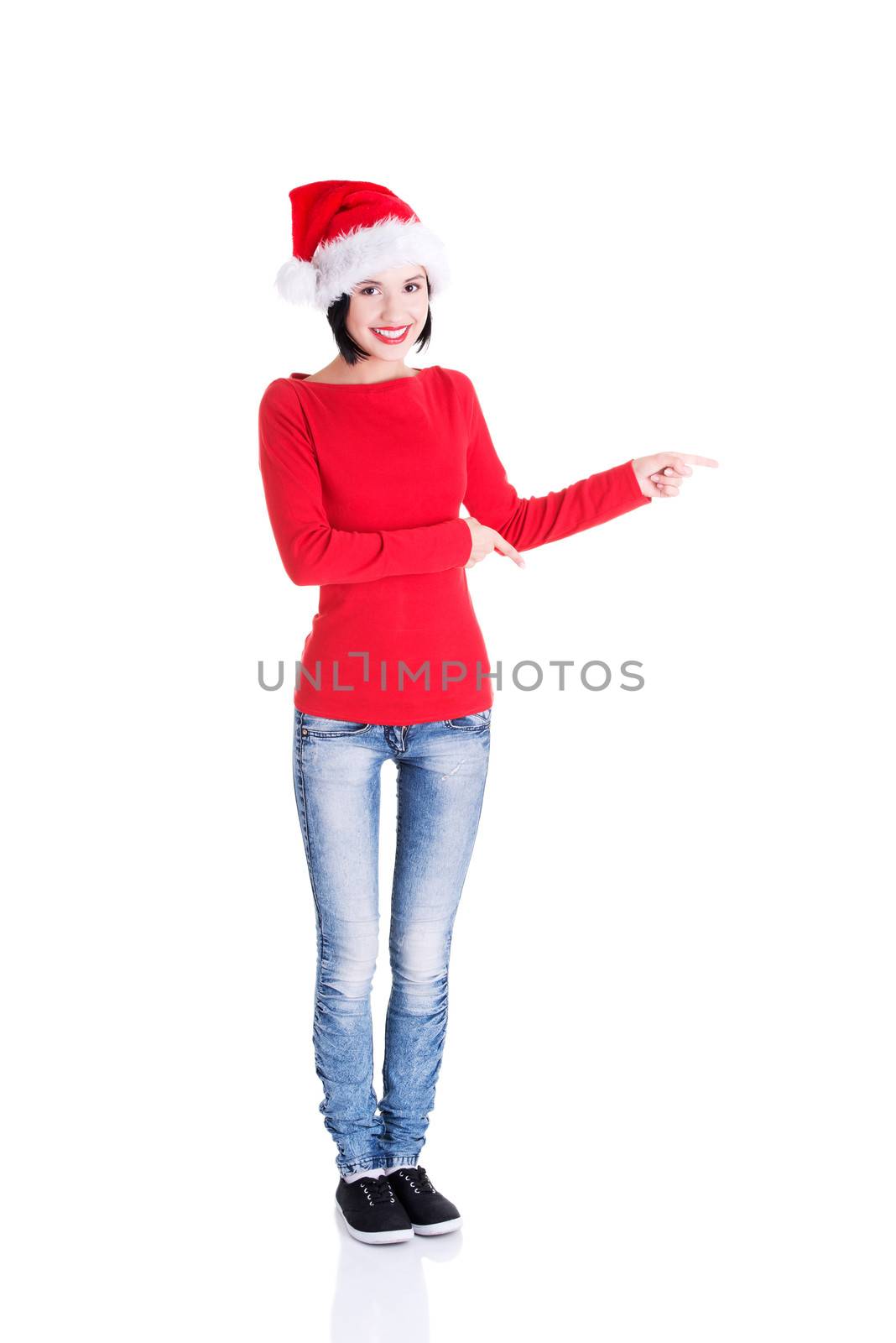 Beautiful smiling christmas santa woman pointing on side showing copyspace. Isolated on white background.