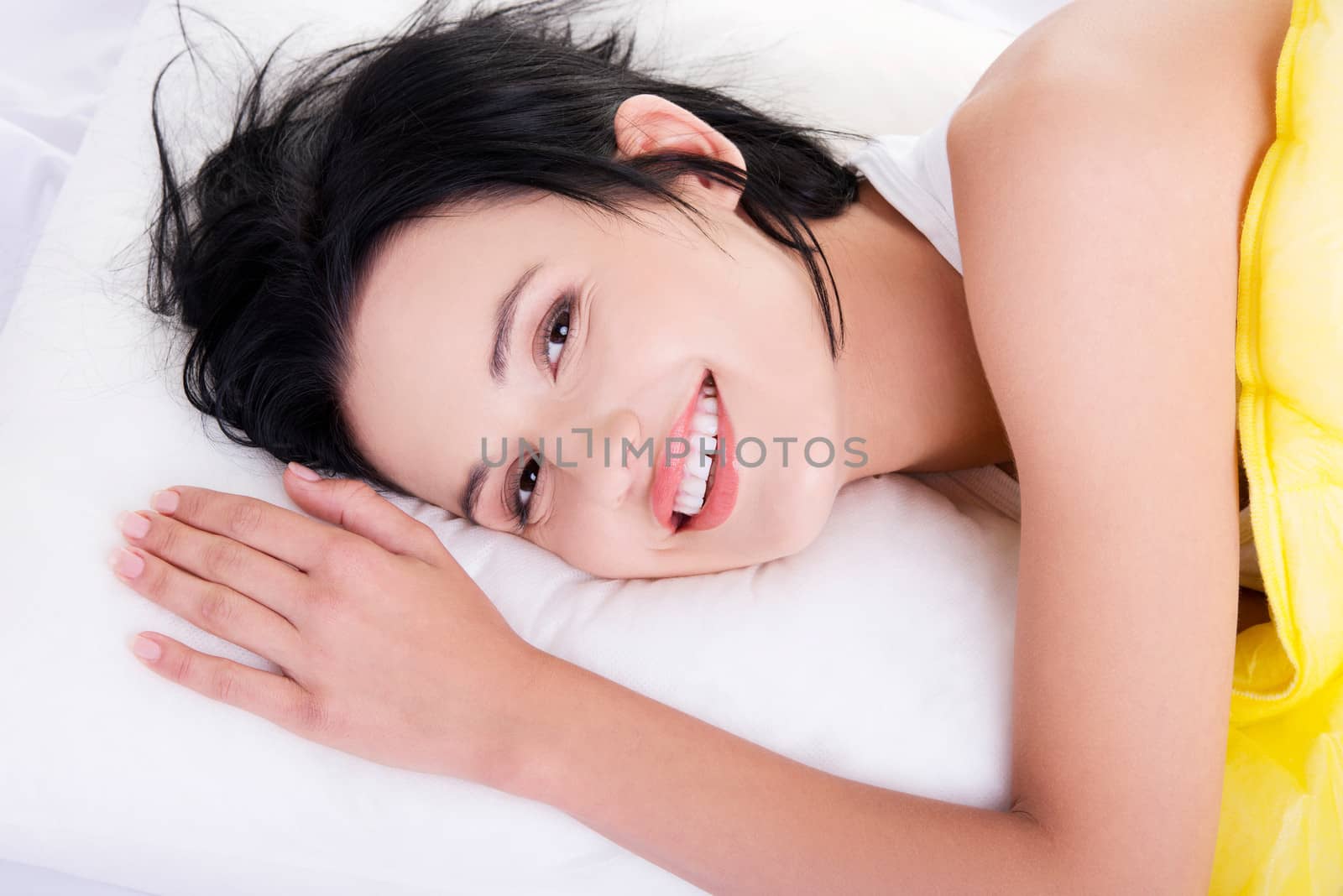 Happy sensual young woman lying in bed and smiling to camera