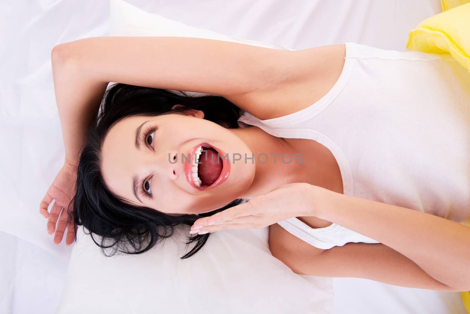 Happy sensual young woman lying in bed and smiling to camera