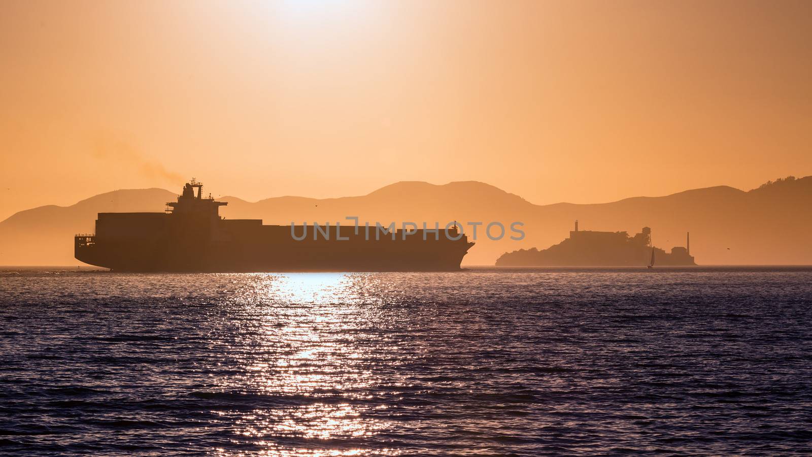 Alcatraz island penitentiary at sunset and merchant ship in san Francisco California USA