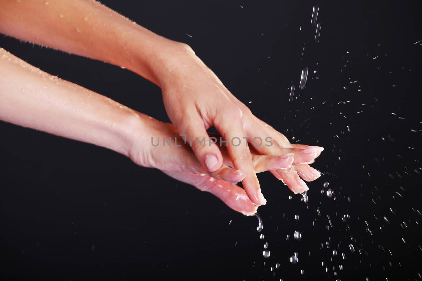 Water falling on female hands, over black background