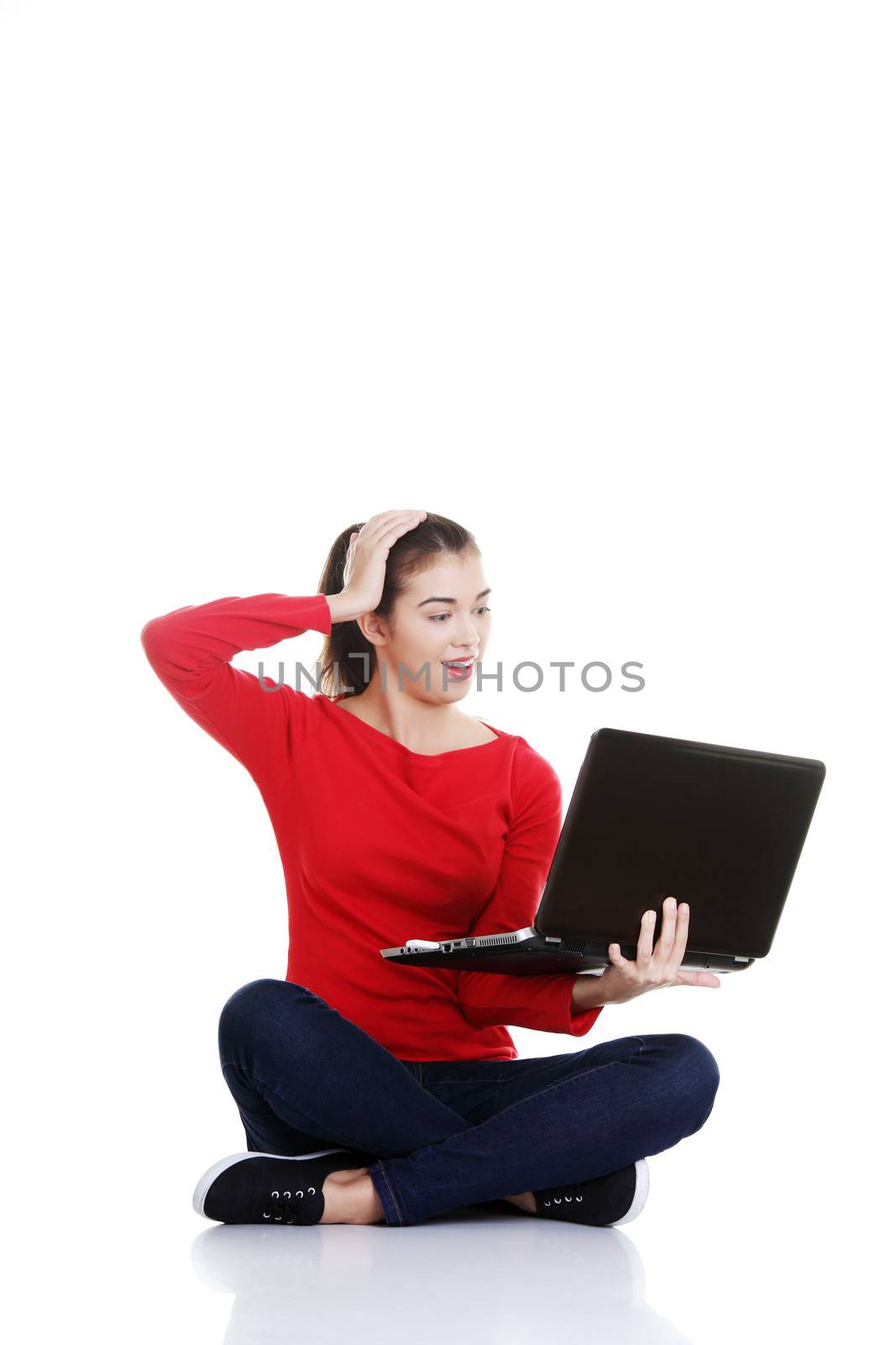 Casual woman sitting with laptop. Isolated on white.