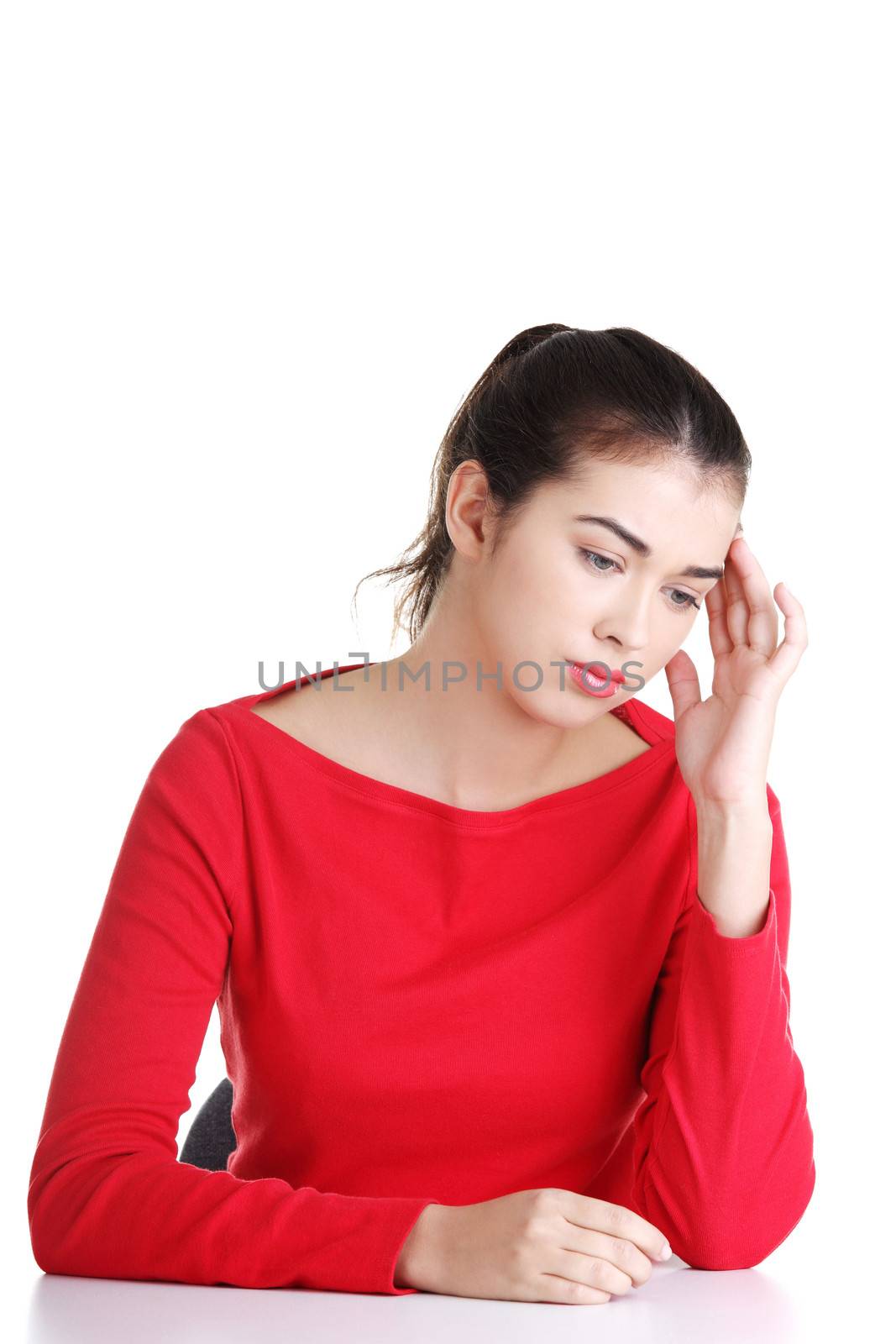 Girl sitting with resigned position. Bored young woman touching her head. Isolated on white background.