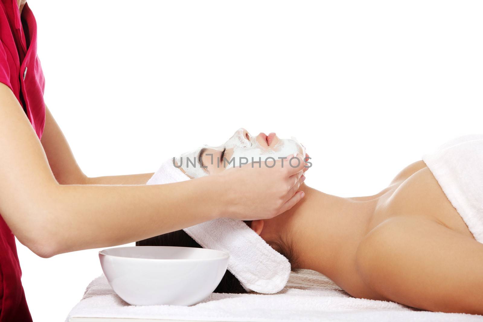 Beauty treatment in spa salon. Woman with facial clay mask.