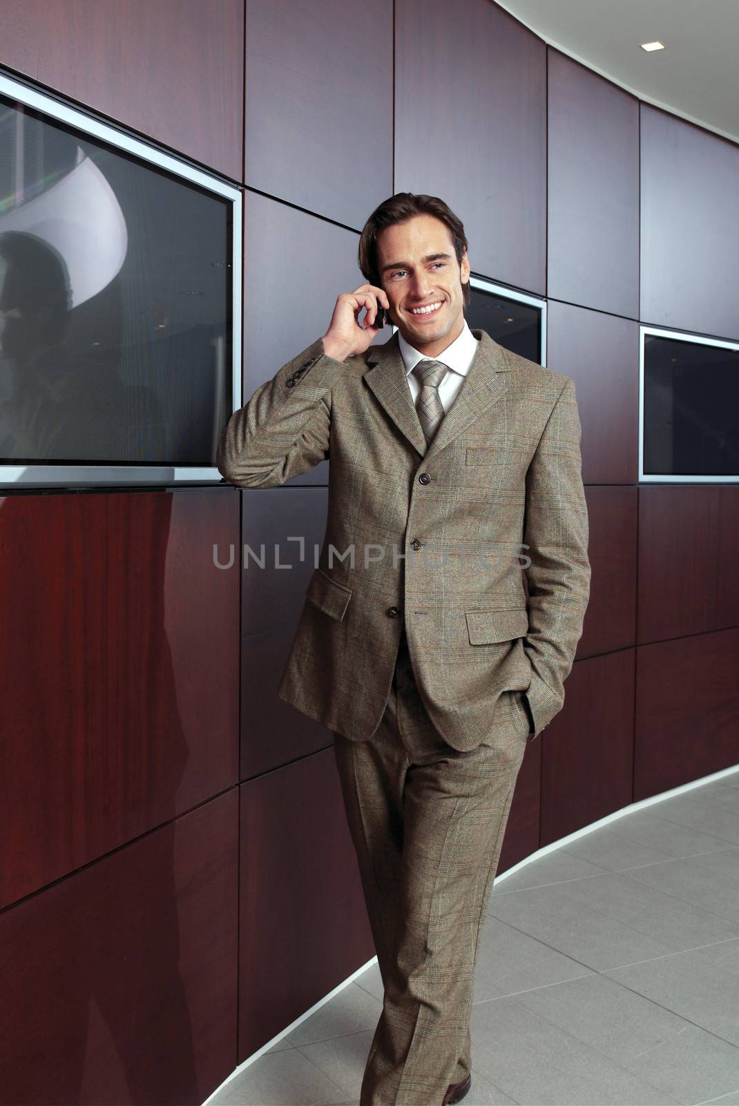 Businessman with mobile phone in front of modern building 