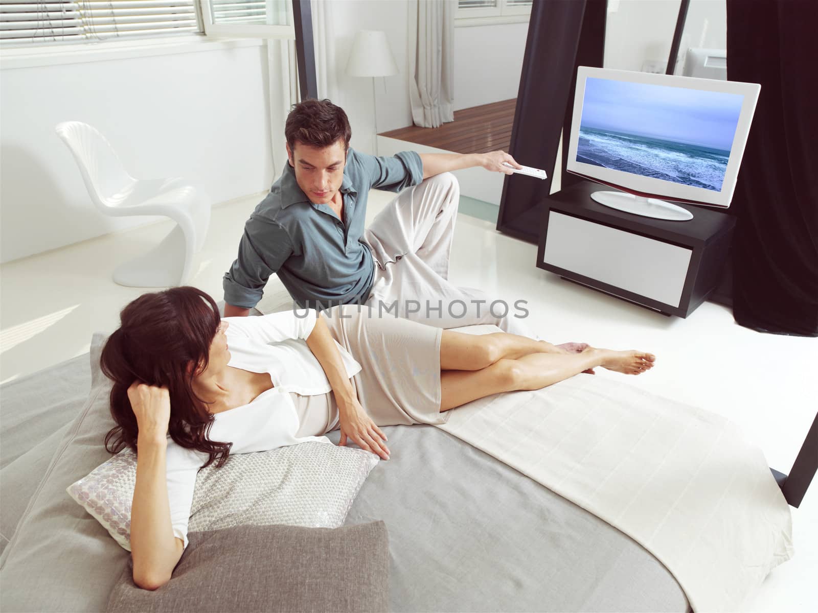 Portrait of happy couple sitting on sofa and watching television together 