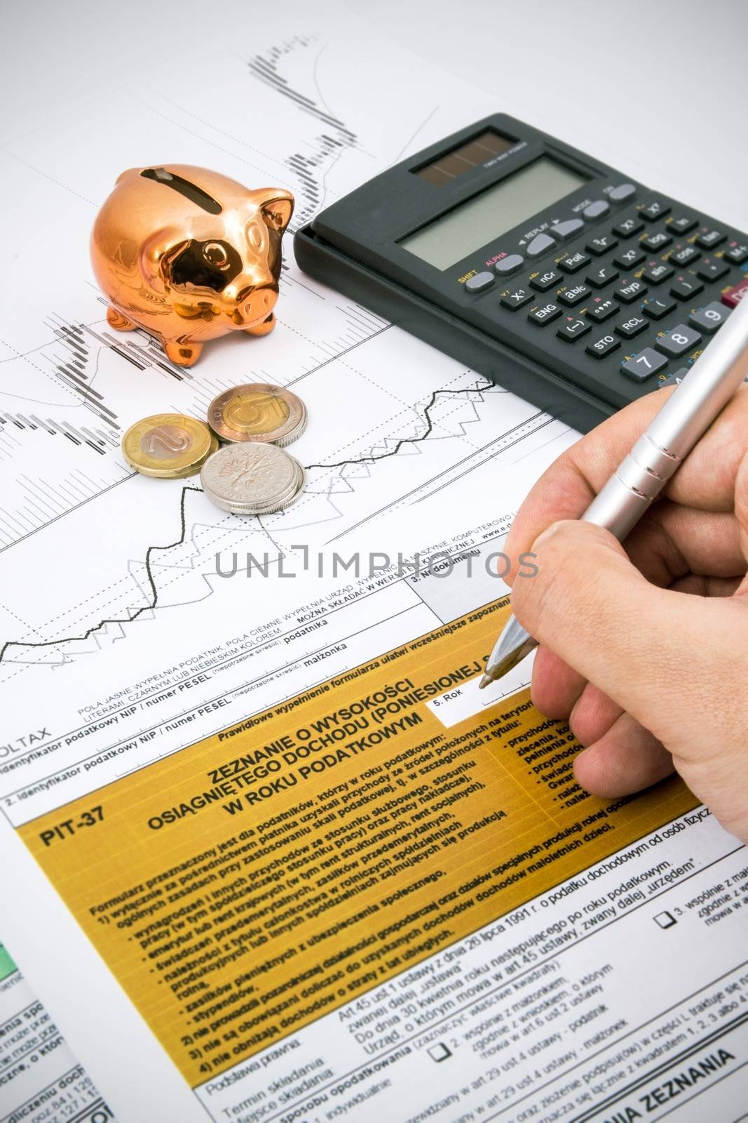 Man hand filling PIT-37 income tax forms with calculator and coins