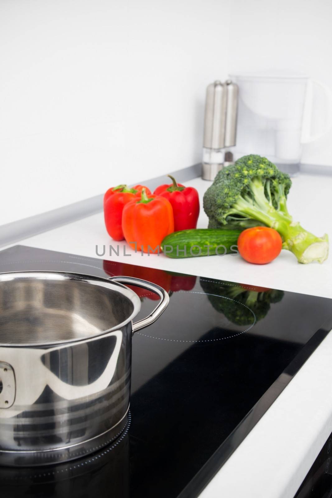 Pot and vegetables in modern kitchen with induction stove