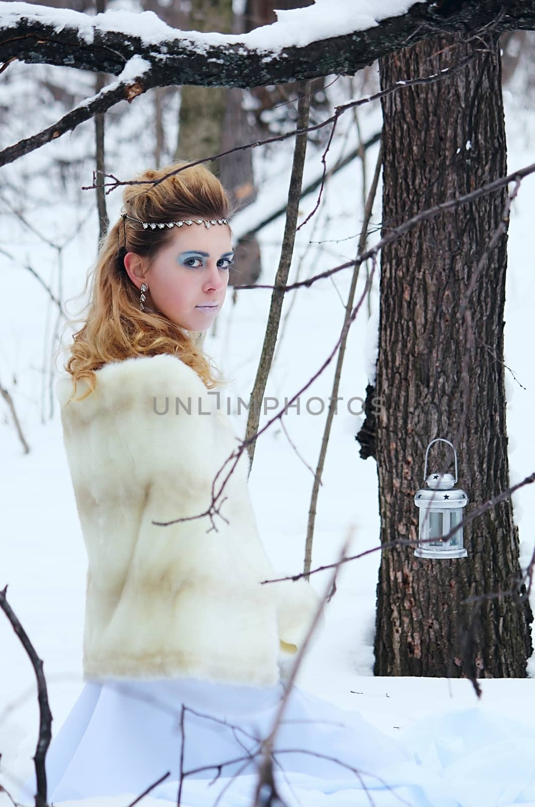Portrait of beautiful girl in the winter forest among white snow