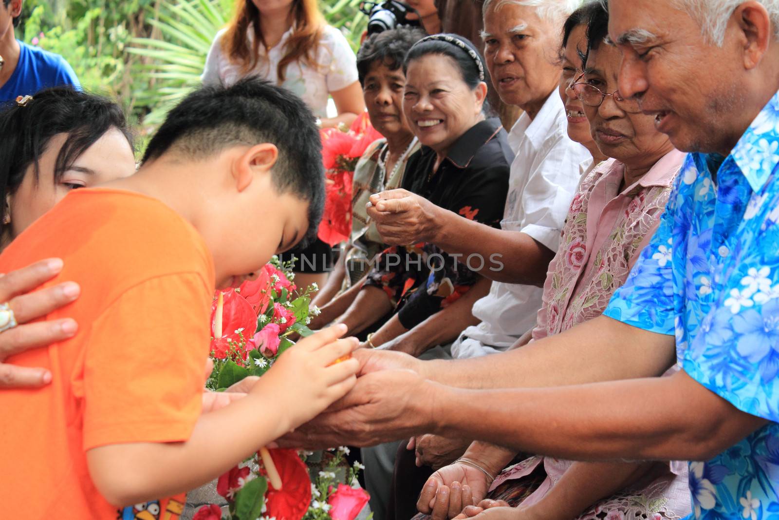 KRABI, THAILAND - APRIL 16: Unidentified Thai boy 10 years old celebrate Songkran (new year / water festival) by giving garlands to their seniors and asked for blessings on April 16, 2013 in Krabi, Thailand.