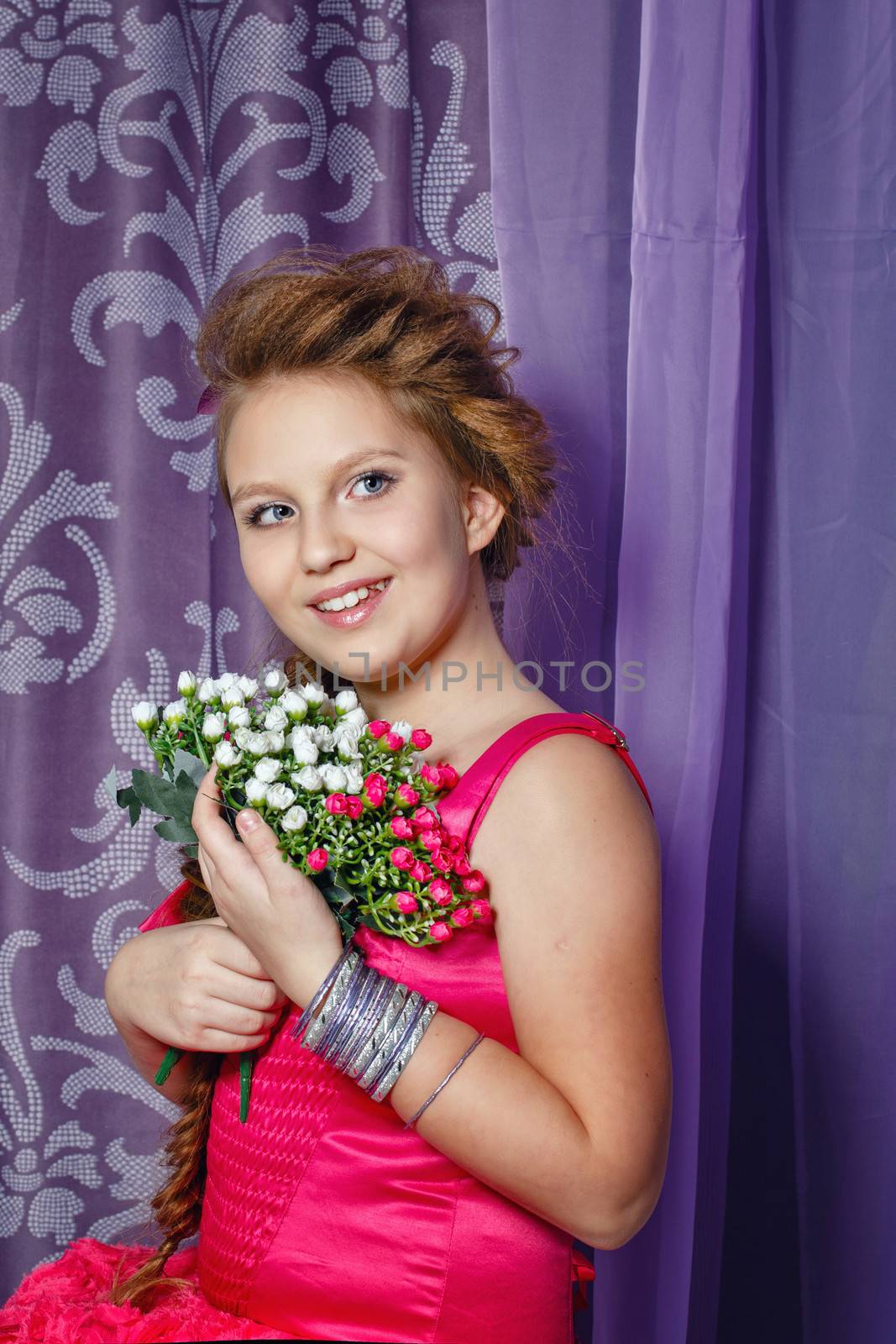 Beautiful little girl in a pink dress with a bouquet of flowers posing in the interior