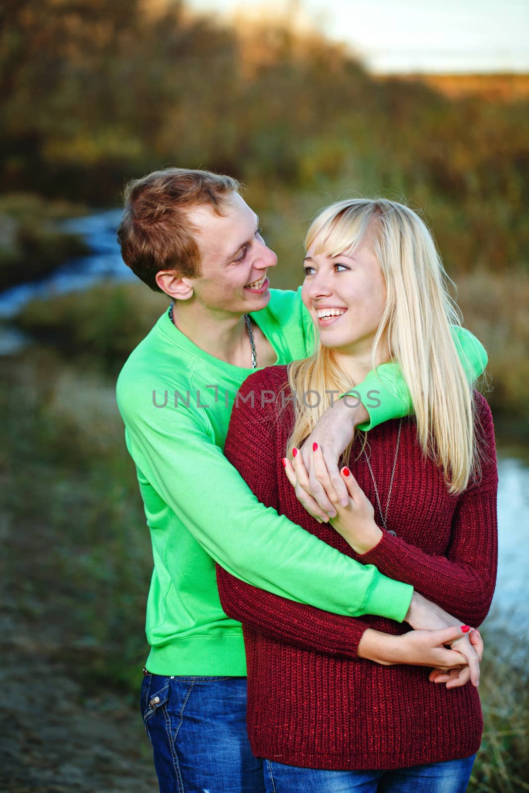 Young couple tenderly and lovingly embrace each other on banks of river