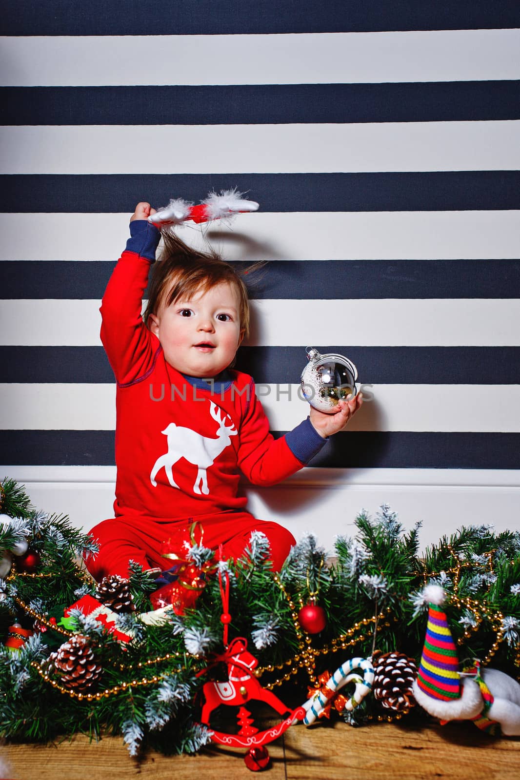 Little boy sitting on the floor surrounded by Christmas decorations