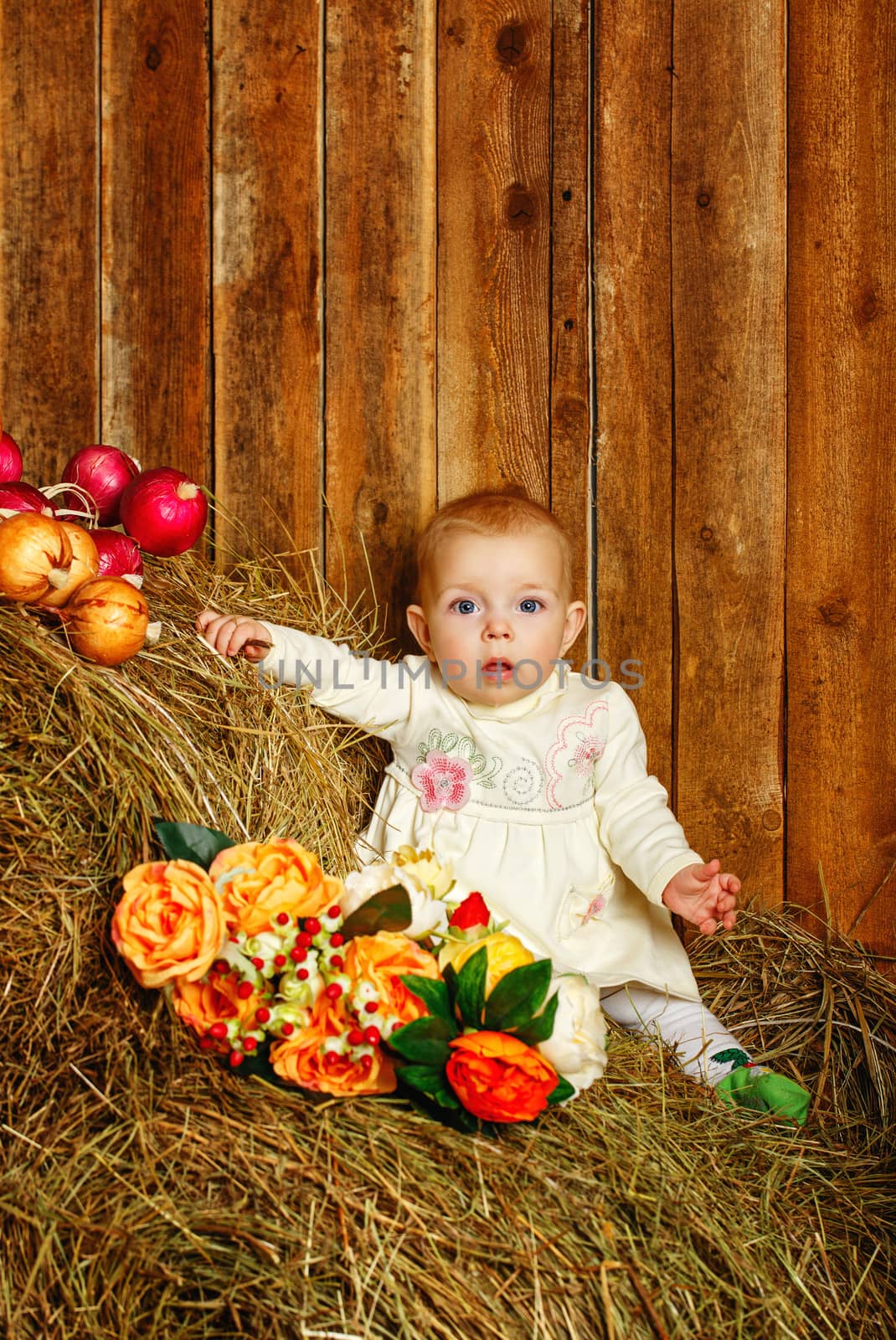 Cute little girl standing on hay in rustic barn