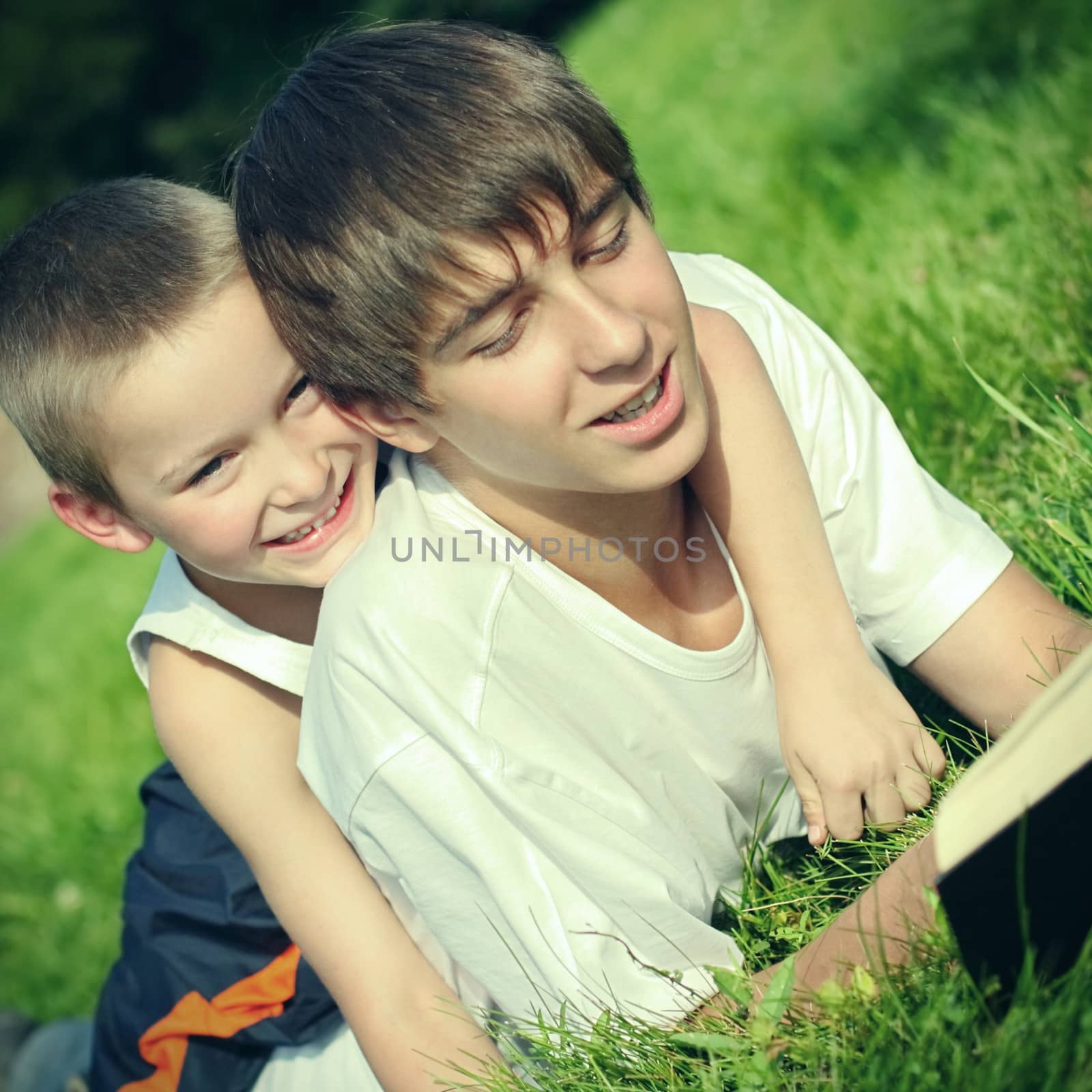 Teenager and Kid with a Book by sabphoto