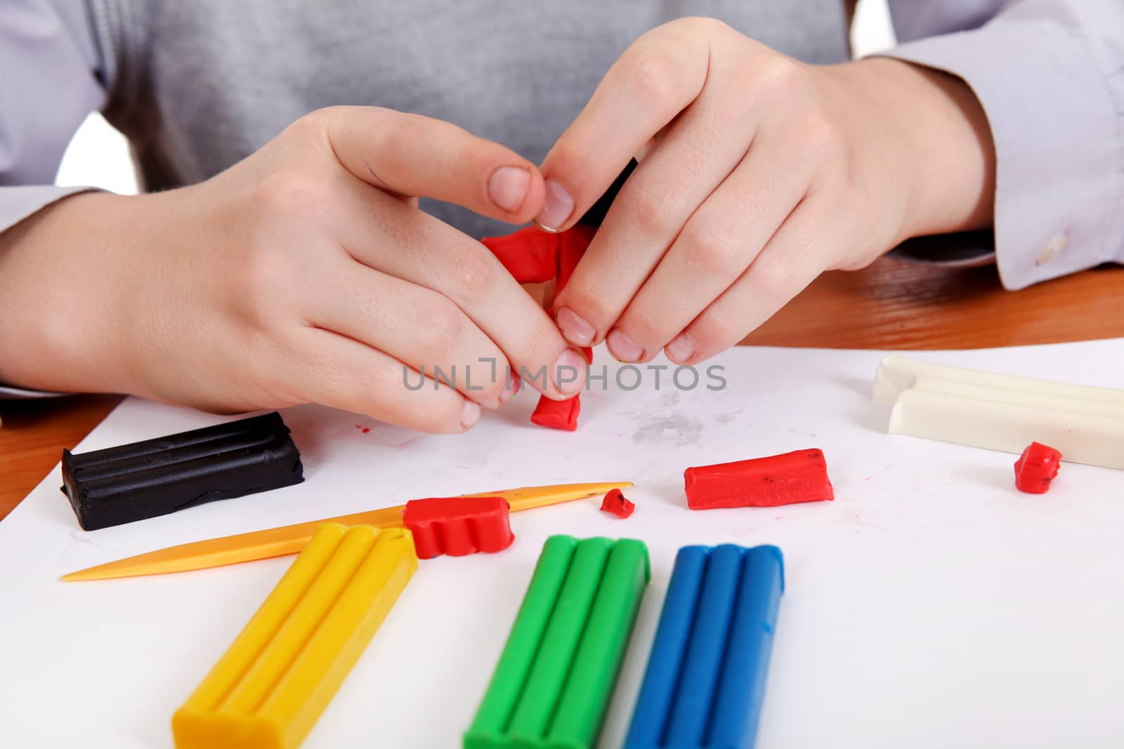 Kid playing with Plasticine at the School Desk Closeup