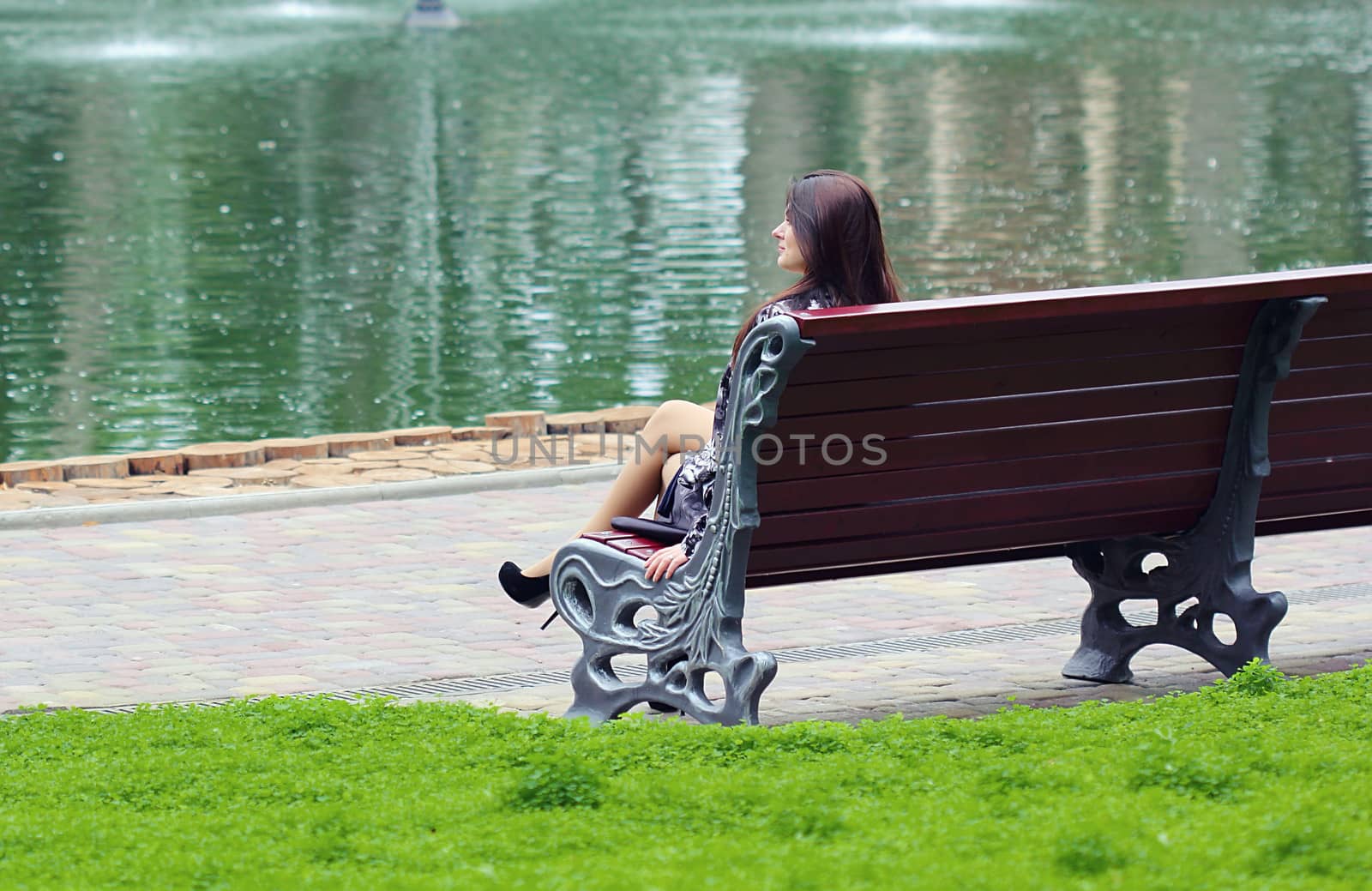 Woman sitting near the river at the bench