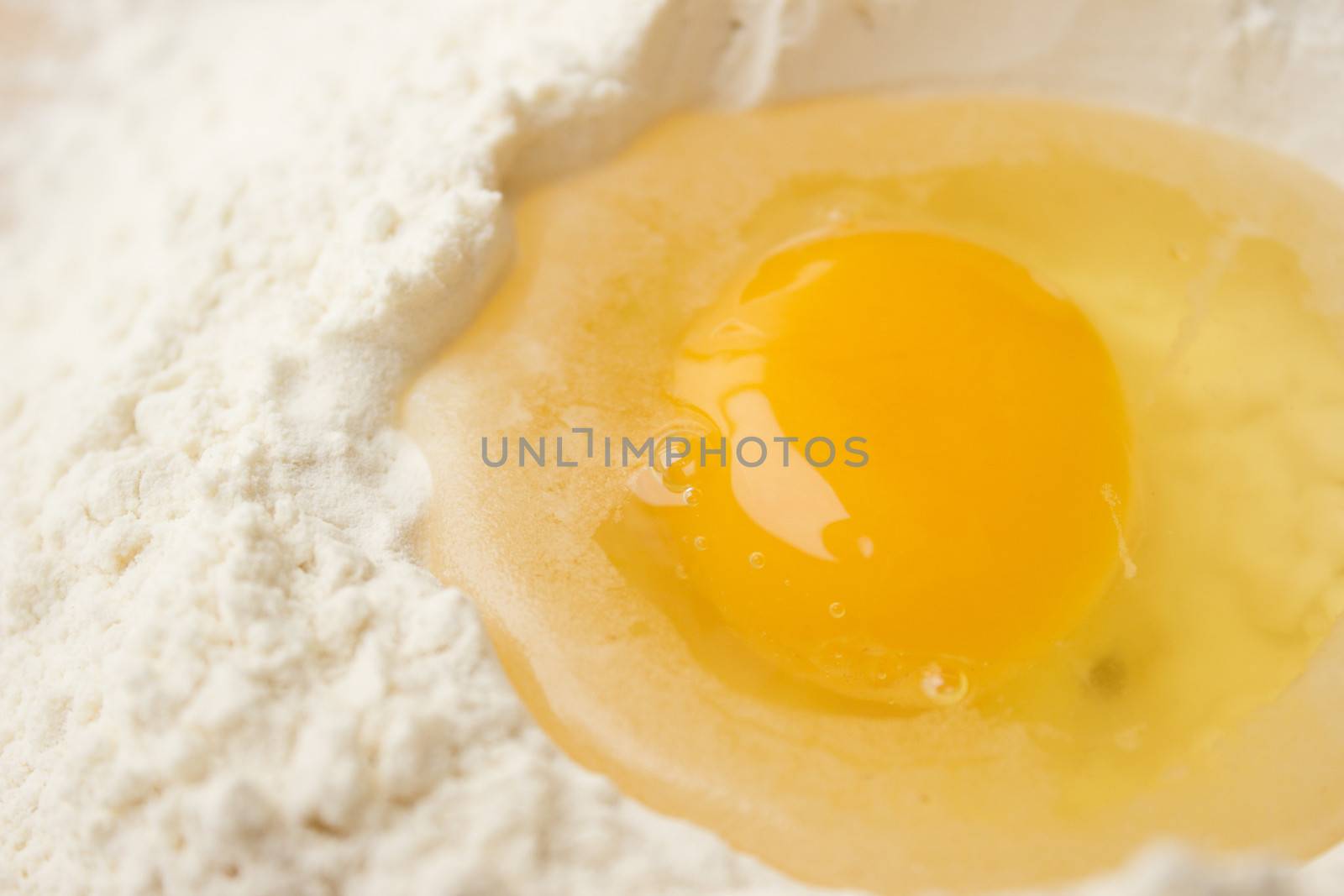 Flour on a wooden cutting board with a egg in the middle of it.