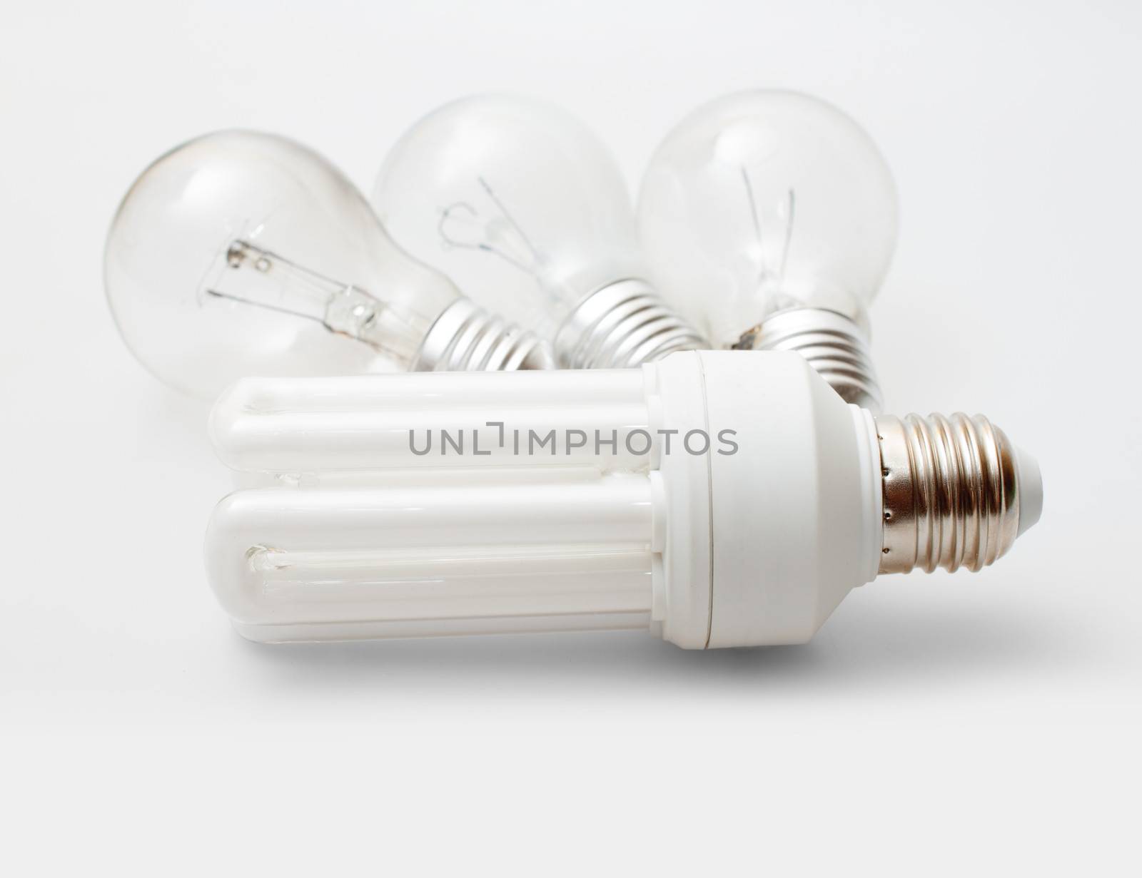 New Energy Saving Bulb and Three Aged Burnt Tungsten Bulbs on Light Background