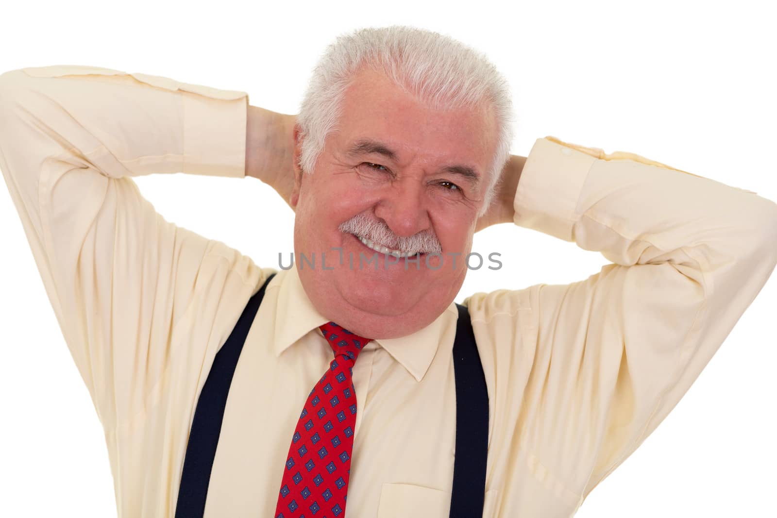Jovial senior man with a moustache and a wide warm smile standing with his hands behind his head looking at the camera