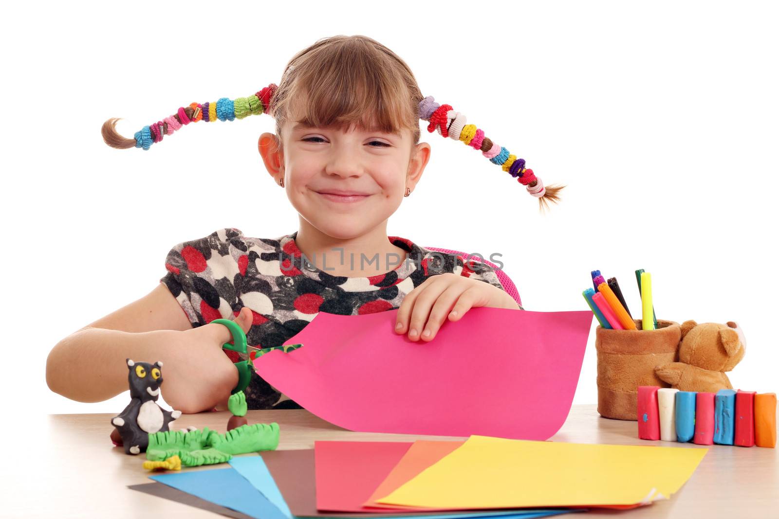 happy little girl cutting paper with scissors by goce