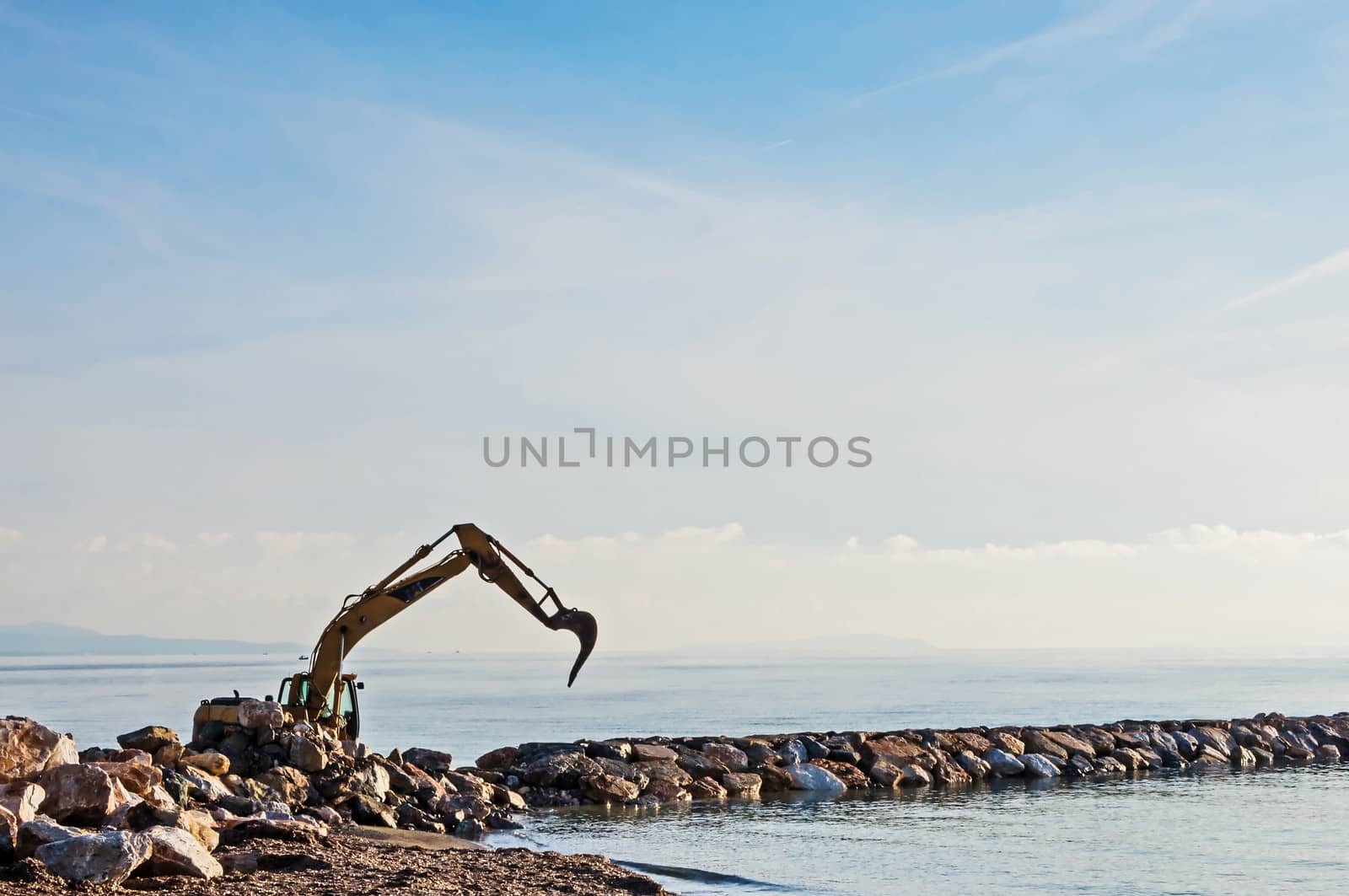 Excavator working to build a dam against beach erosion