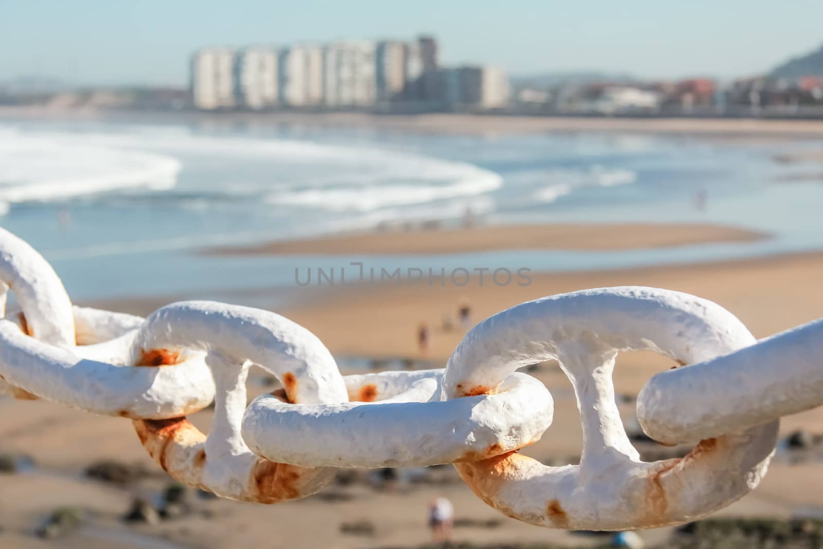 Closeup of metal chain fence over city beach background