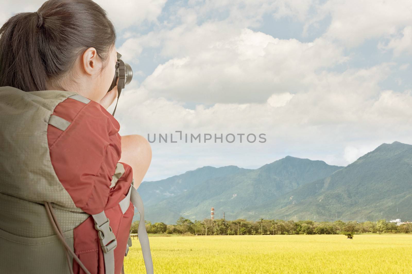 Young backpacker travel and take picture at rural with golden paddy farm under sky in Taiwan.