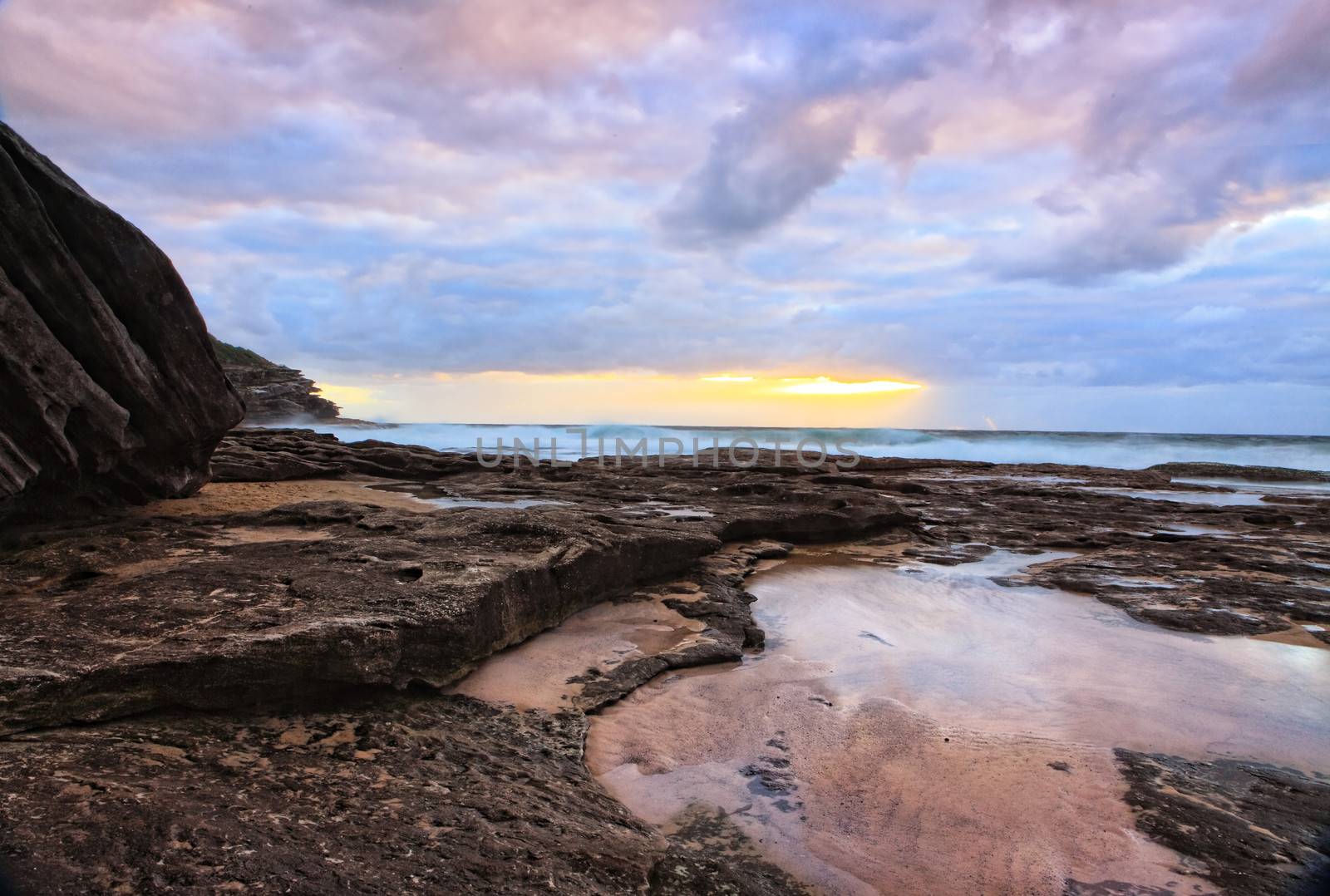 The suns rays break through the clouds at Mackenzies Bay, Australia, colouring the sky.