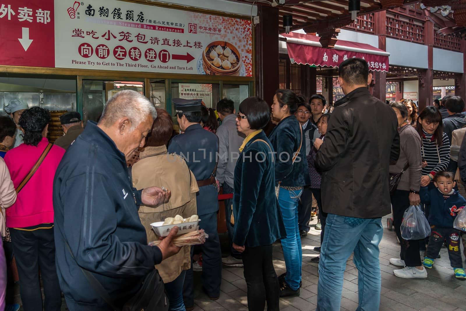 Shanghai, China - April 7, 2013: people eating dim sum Shanghai style steamed pork dumplings in Fang Bang Zhong Lu old city at the city of Shanghai in China on april 7th, 2013