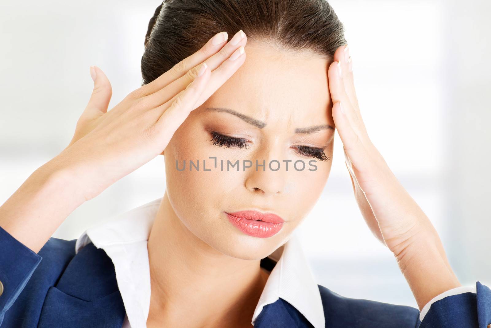 A businesswoman with a headache holding head, isolated on white background