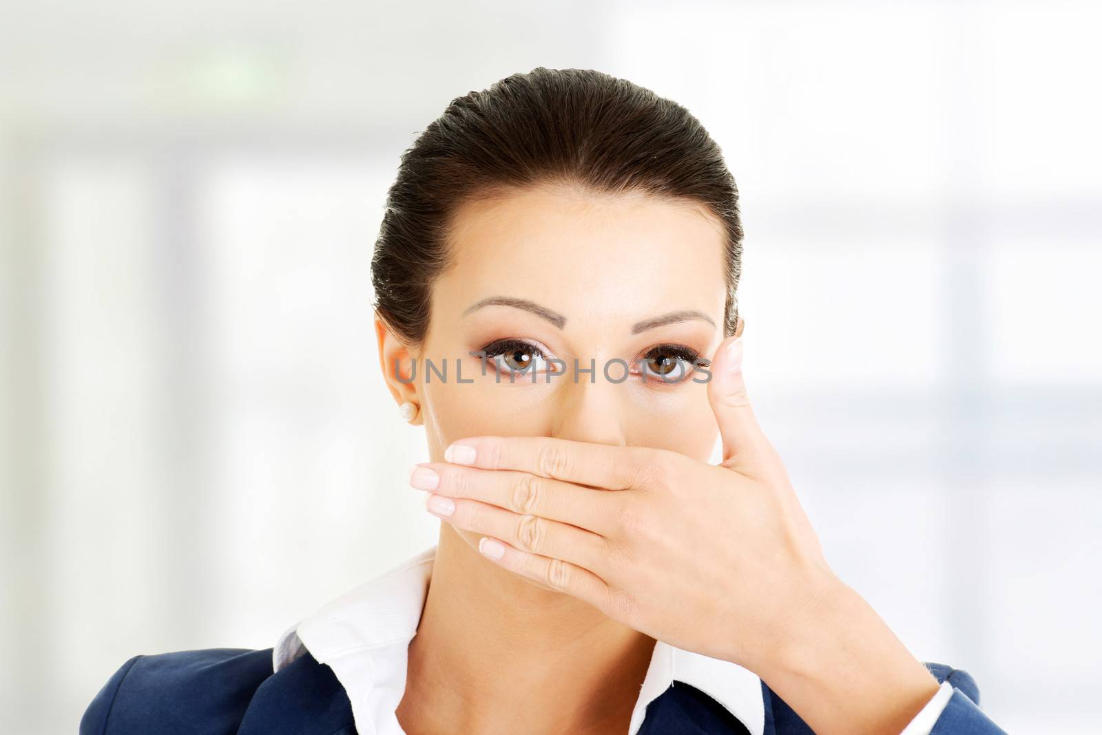 Portrait of young business woman covering with hand her mouth, isolated on white background