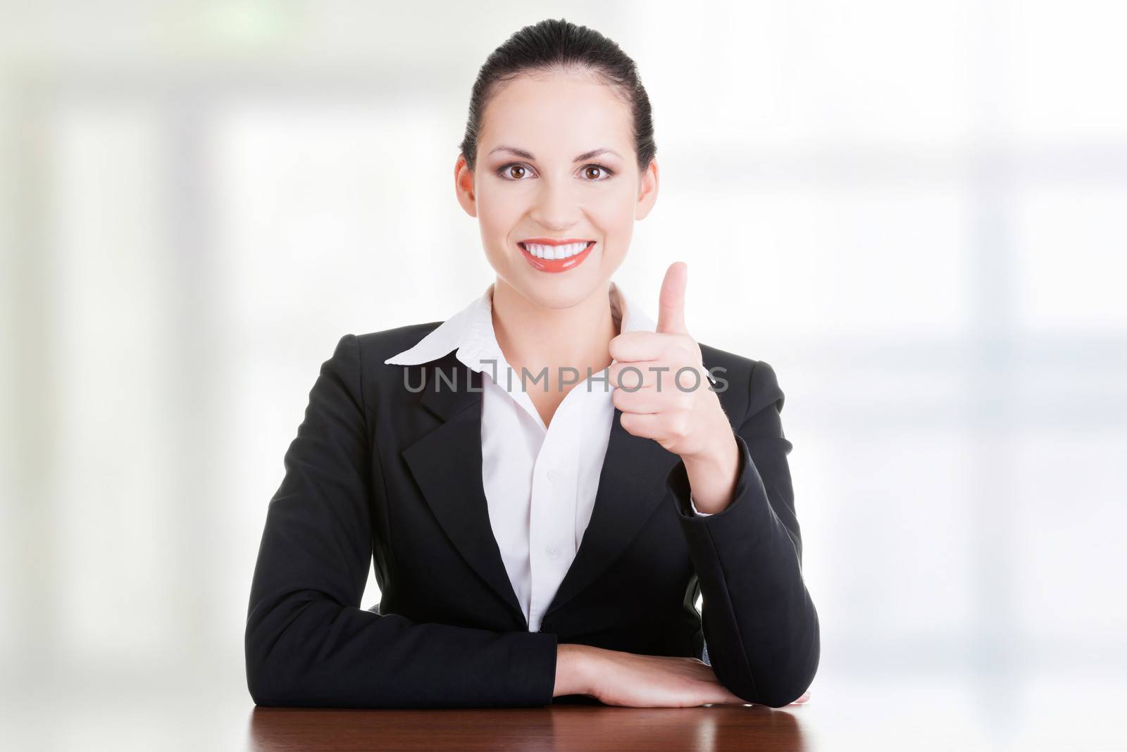 Young woman at the desk gesturing OK by BDS