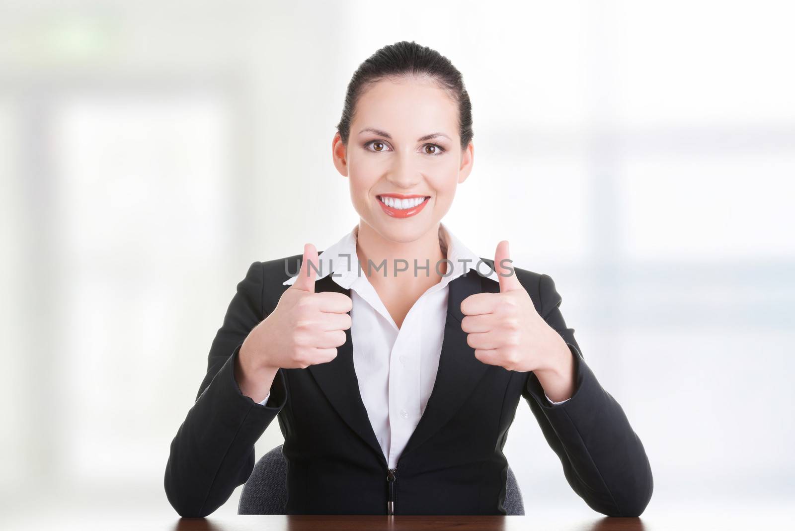 Young woman at the desk gesturing OK , isolated on white