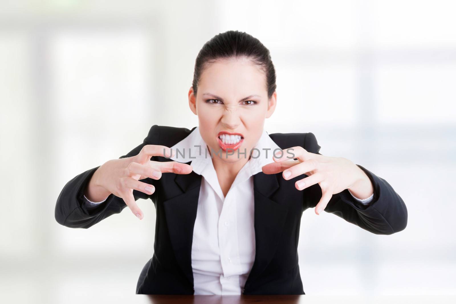 Angry businesswoman at the desk, isolated on white background