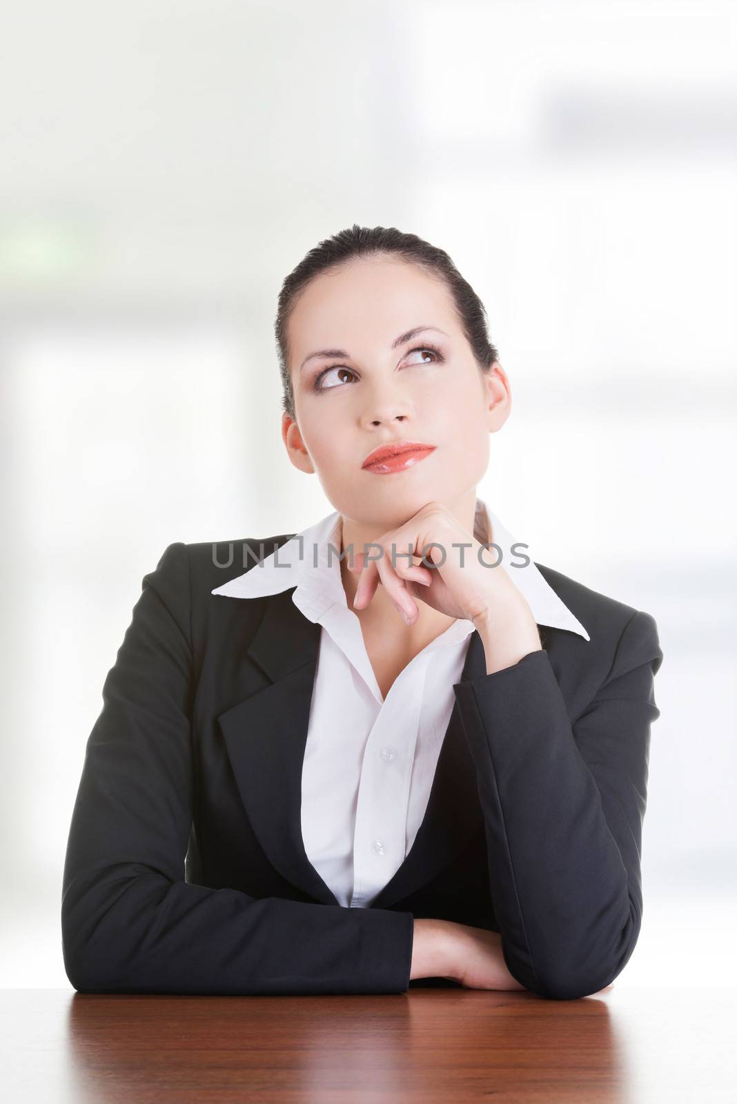 Pretty business woman in sitting at the desk and thinking, isolated on white