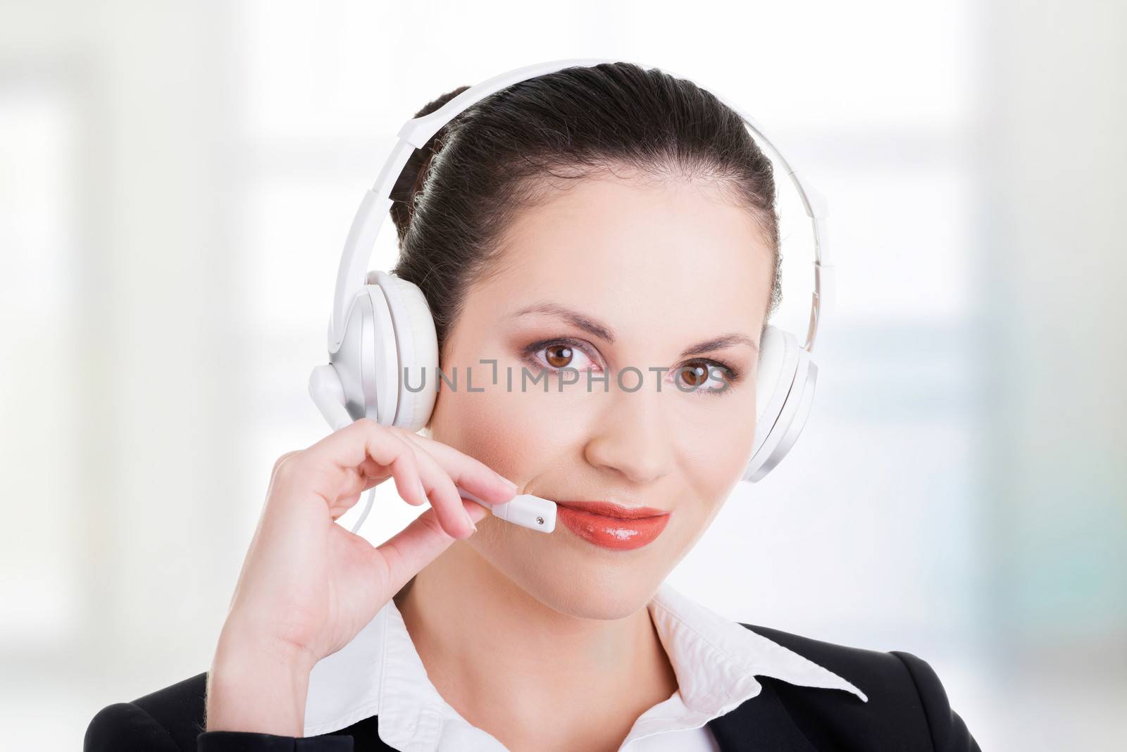 Beautiful young call-center assistant at the desk, isolated on white