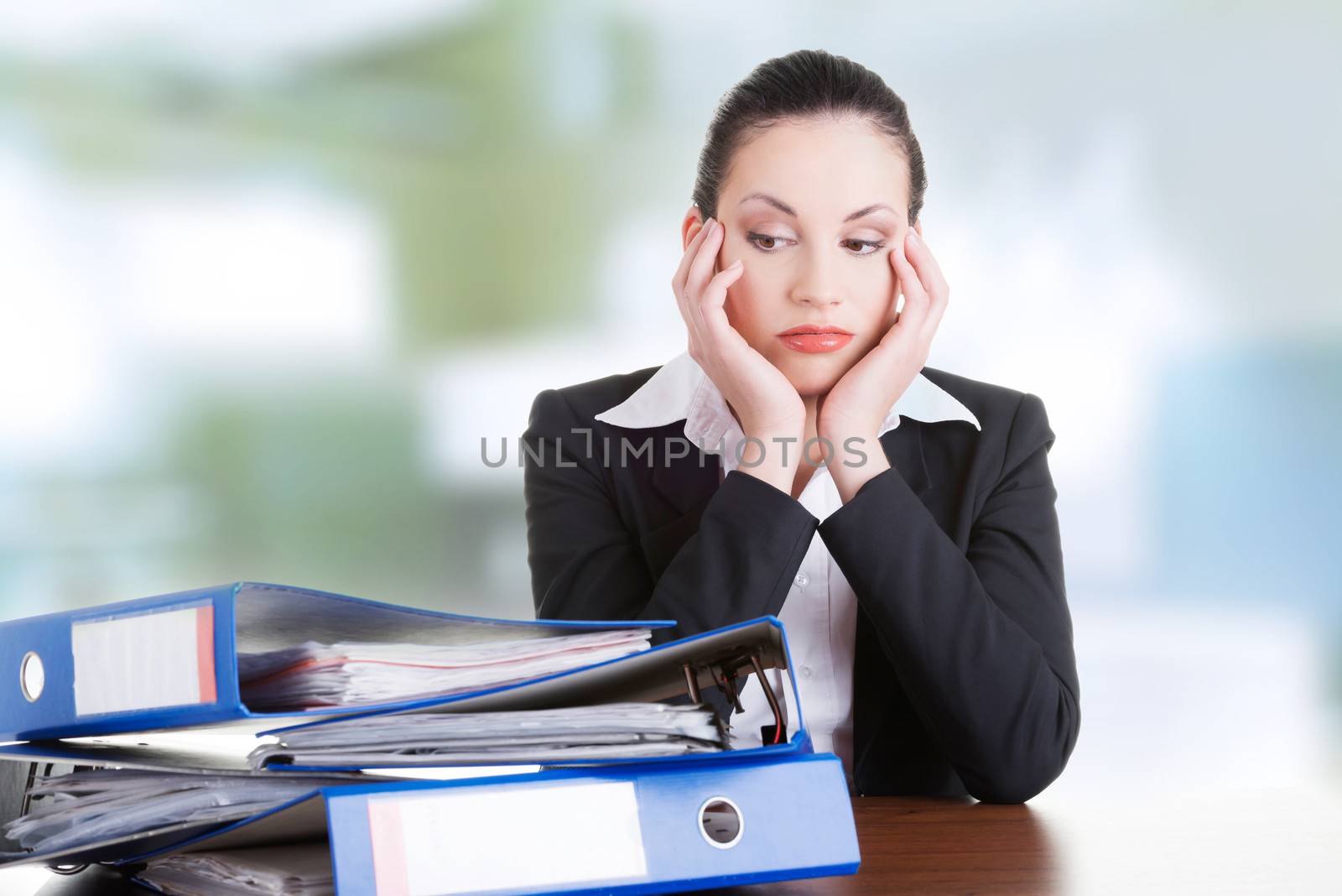 Sad woman with ringbinders sitting at the desk. Tired and exhousted business woman.