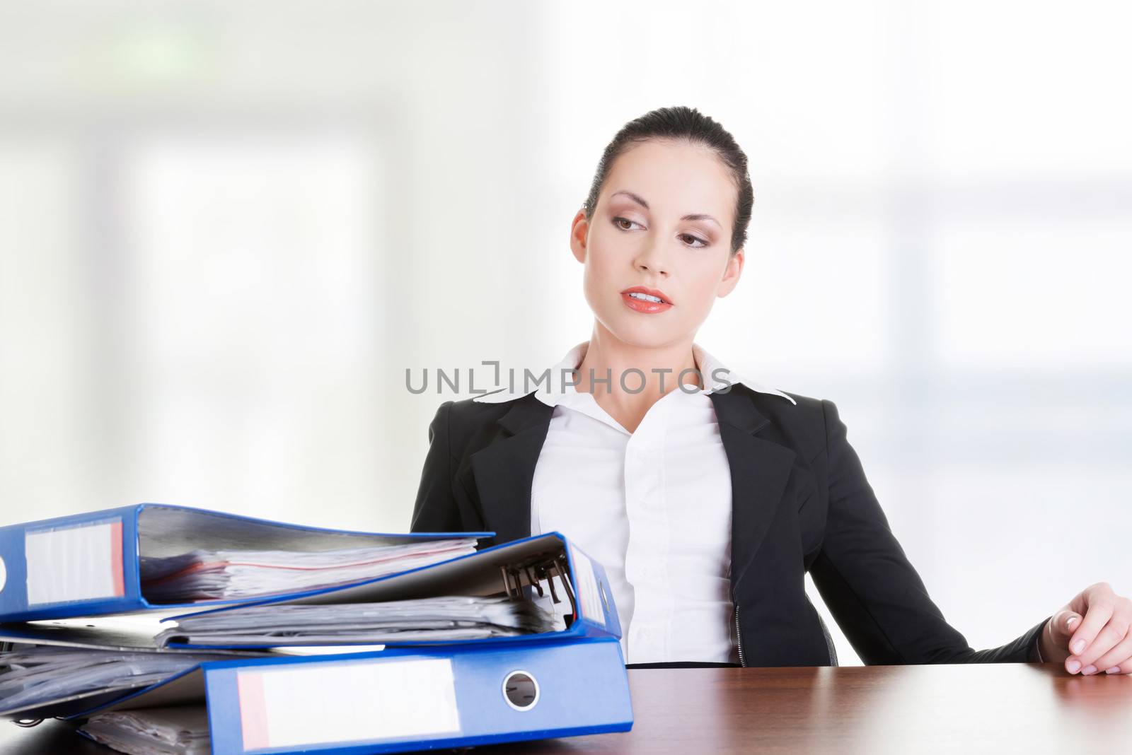 Sad woman with ringbinders sitting at the desk. Tired and exhousted business woman.