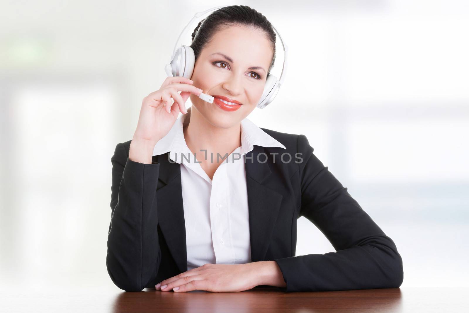 Beautiful young call-center assistant at the desk by BDS